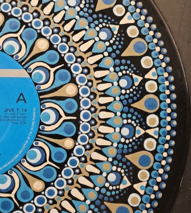 Close-up of hand-painted blue, turquoise, cream, and tan dots and teardrop shapes on an A Flock of Seagulls vinyl record.