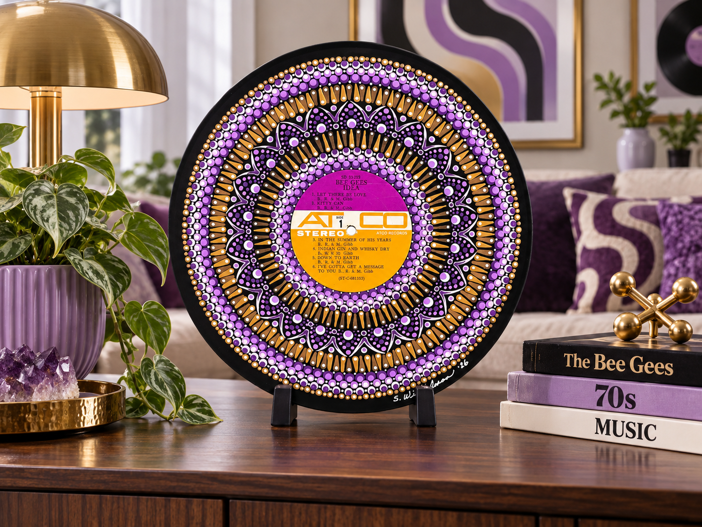 Bee Gees Idea hand-painted vinyl record art displayed on a tabletop stand in a room with purple and gold accent décor