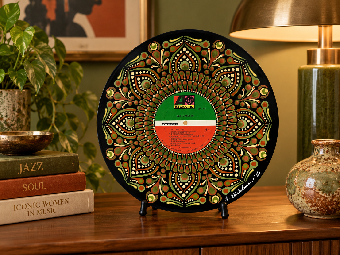 Bette Midler hand-painted vinyl record art displayed unframed on a tabletop stand in a warm room with green and rust accents