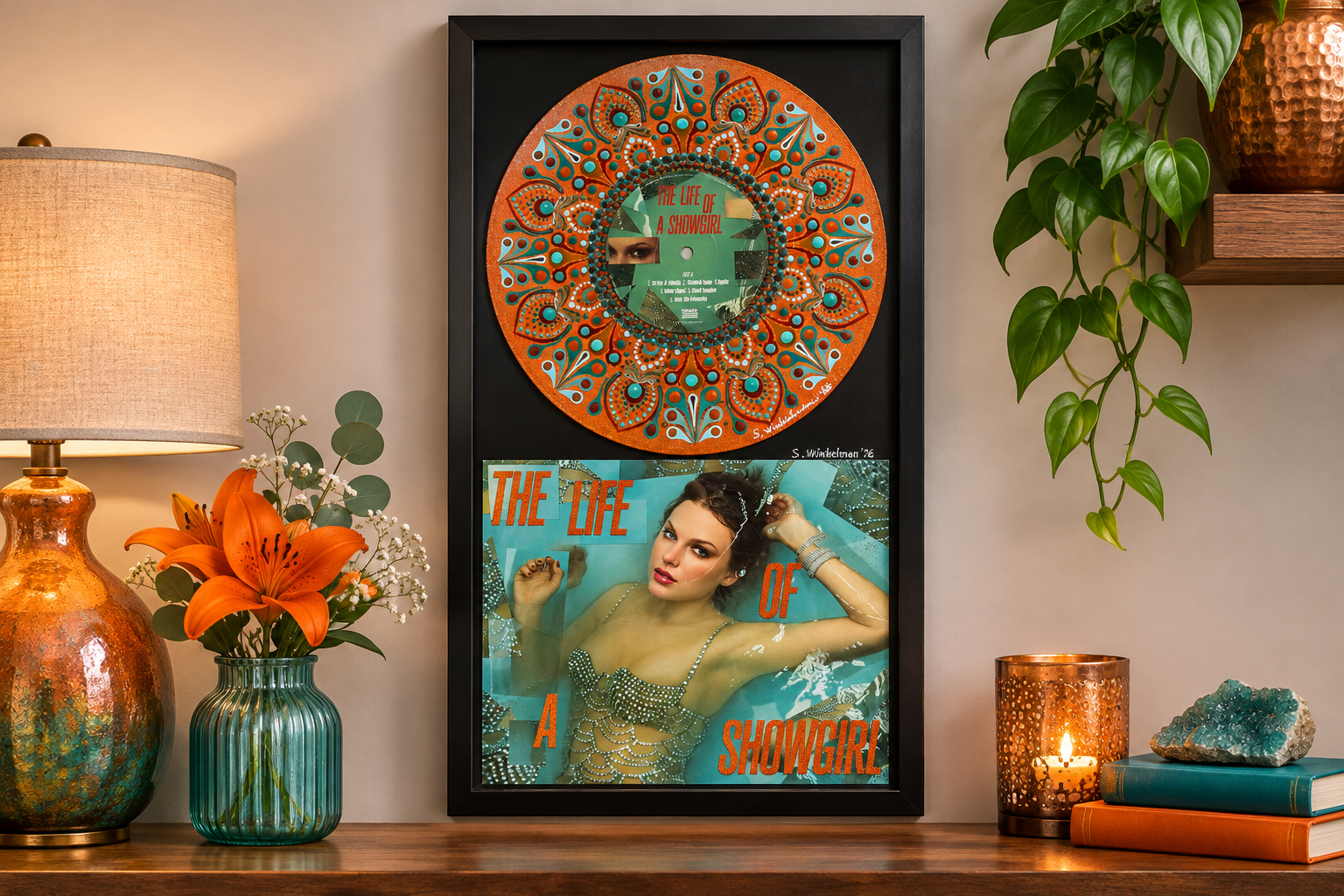 Framed Taylor Swift The Life of a Showgirl vinyl record art displayed on a wooden console with orange flowers, a turquoise vase, warm lamp lighting, and green plants.