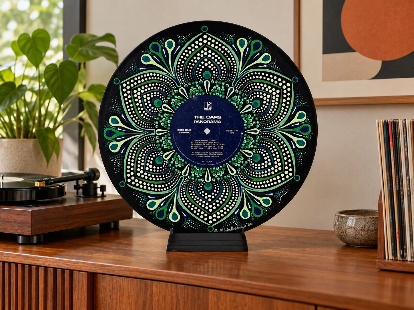 The Cars Panorama hand-painted vinyl record art displayed on a tabletop stand in a contemporary music room