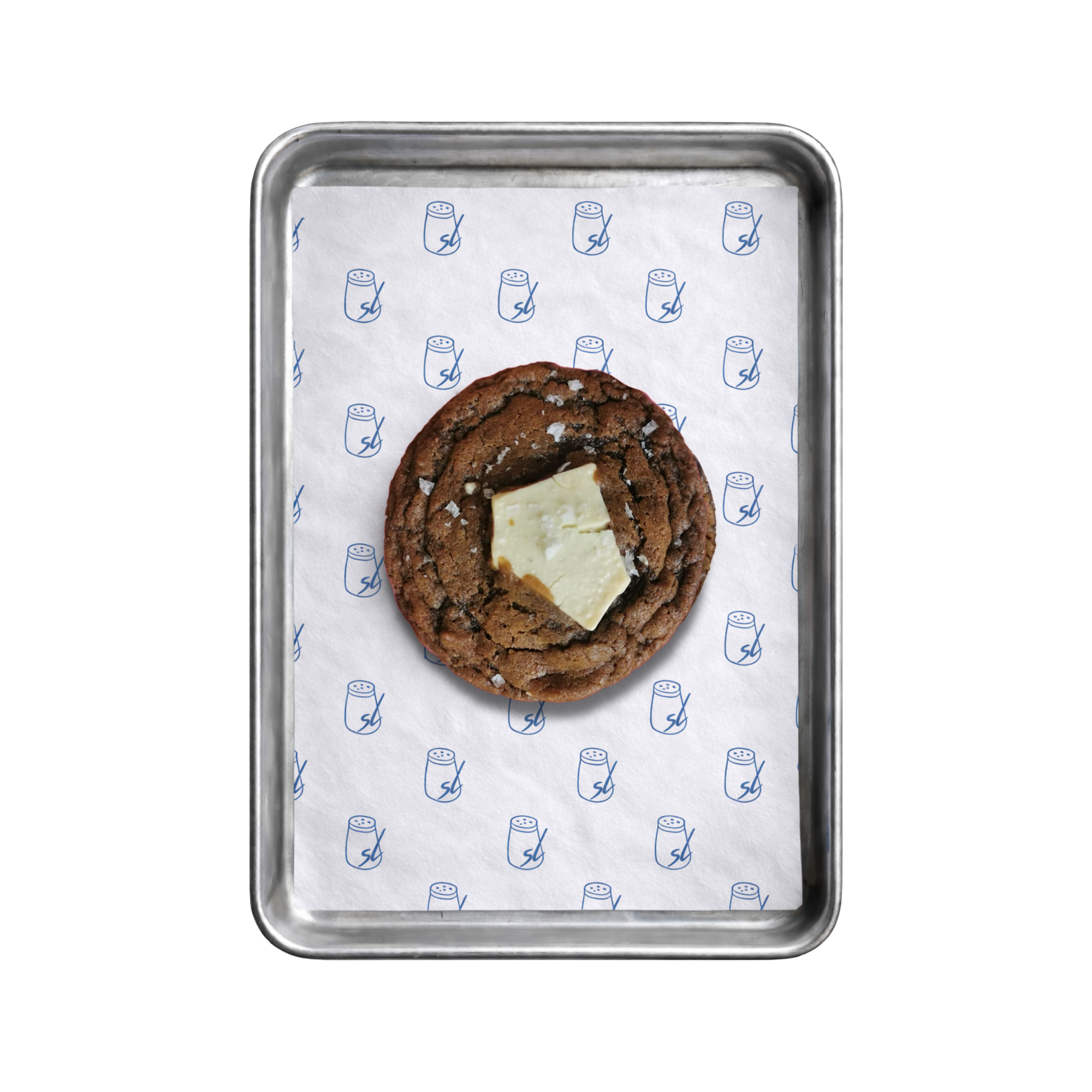 Close-up of a metal tray with a sheet of white paper featuring small salt shakers printed in blue. A large espresso and white chocolate chip cookie is visible in the middle of the tray.