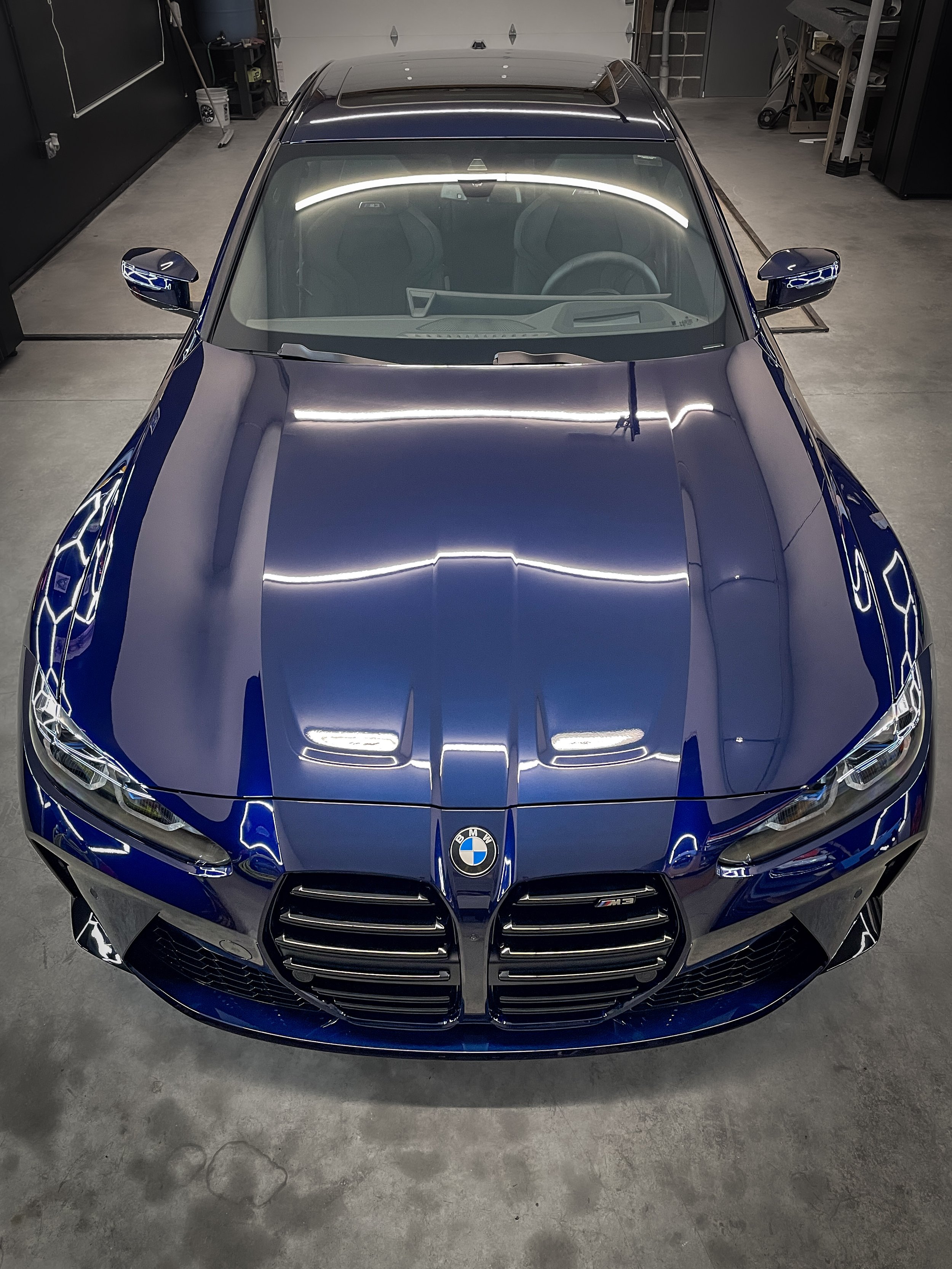 Blue BMW M3 sports car viewed from above inside a garage.
