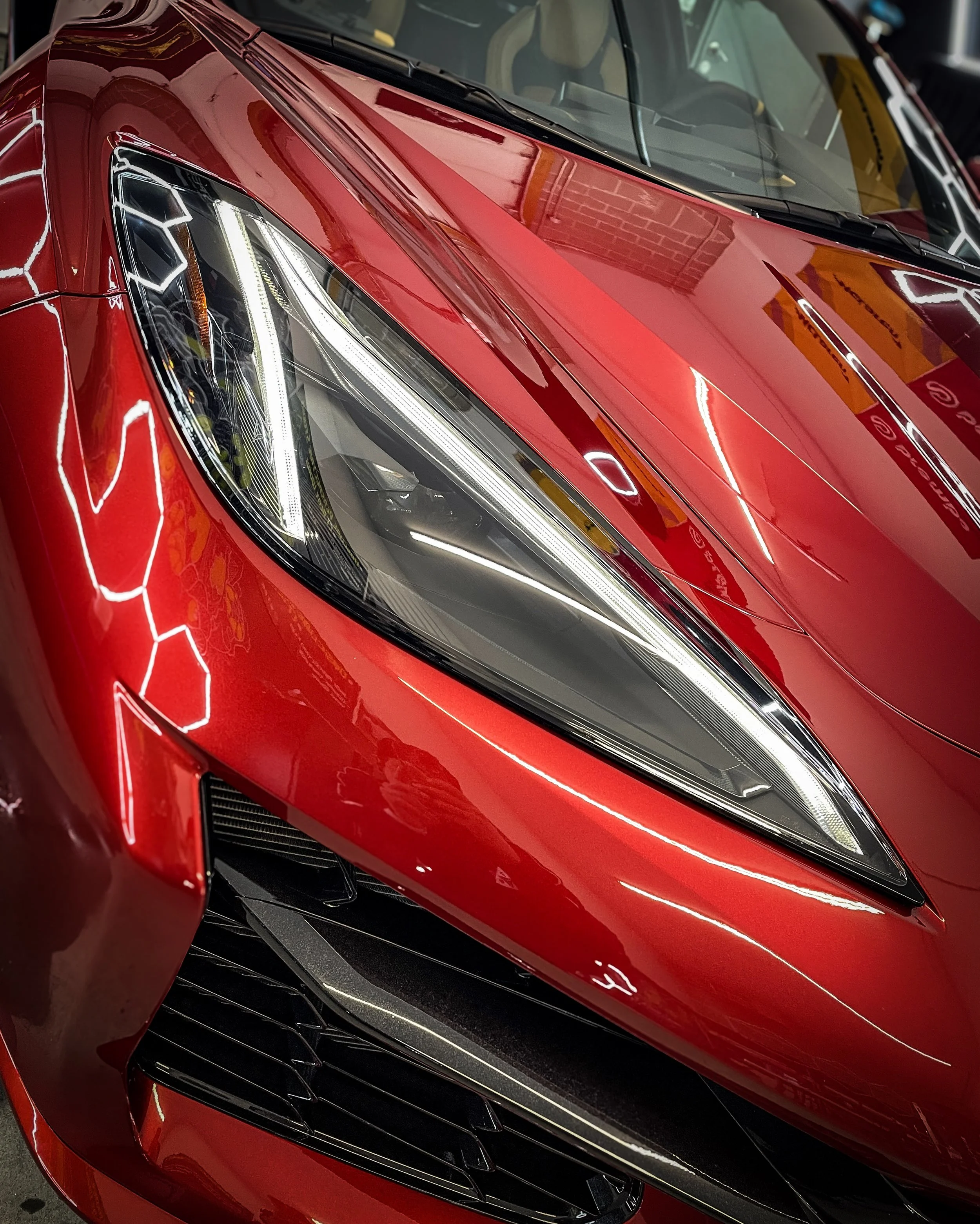 Close-up of a red sports car with sleek headlight design and black accents.