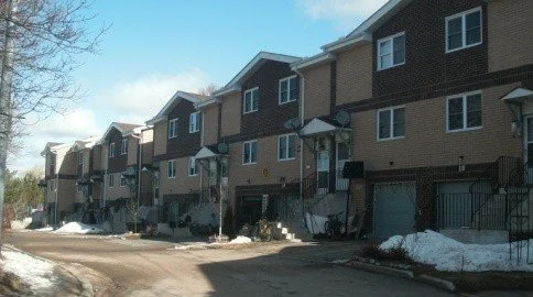 Row of modern townhouses with snow on the ground.