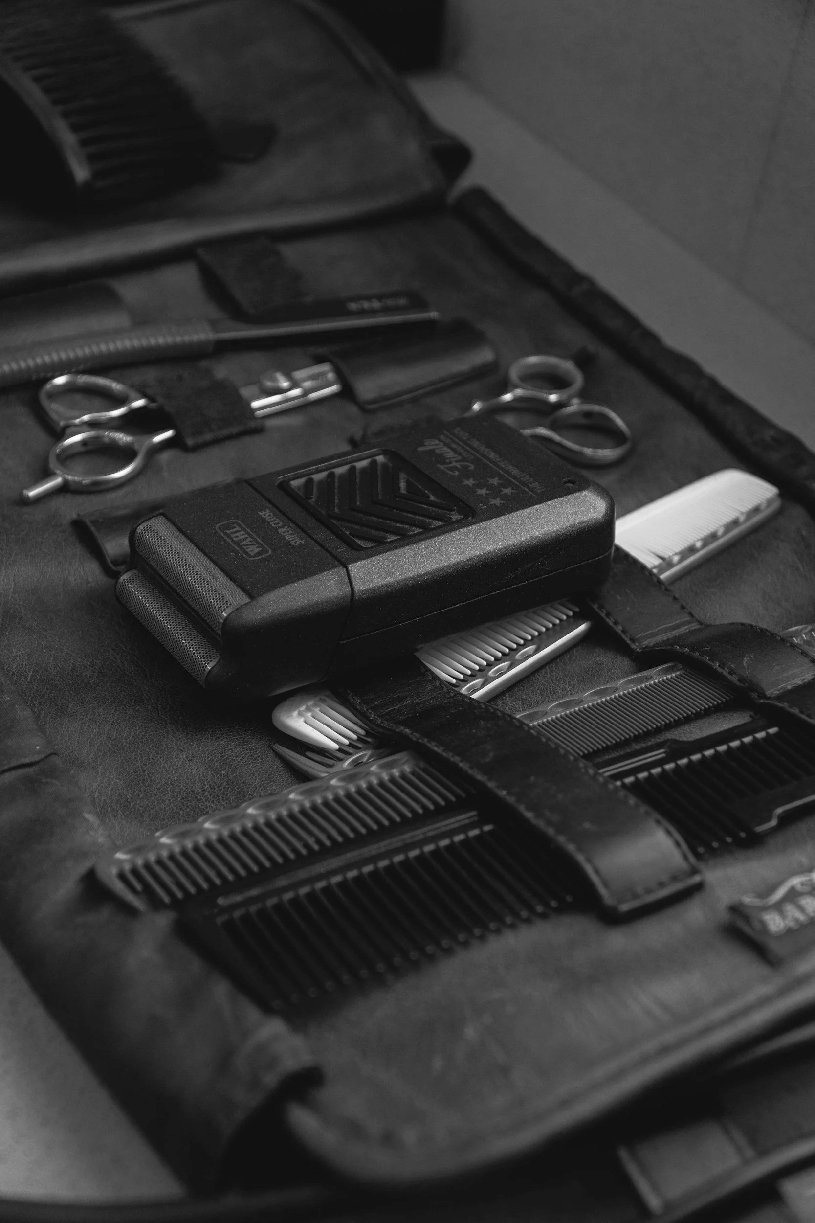 Scherm beim Frisieren mit verschiedenen Friseurutensilien wie Haarschneidemaschinen, Kämme, Scheren, Klammern und Messern.