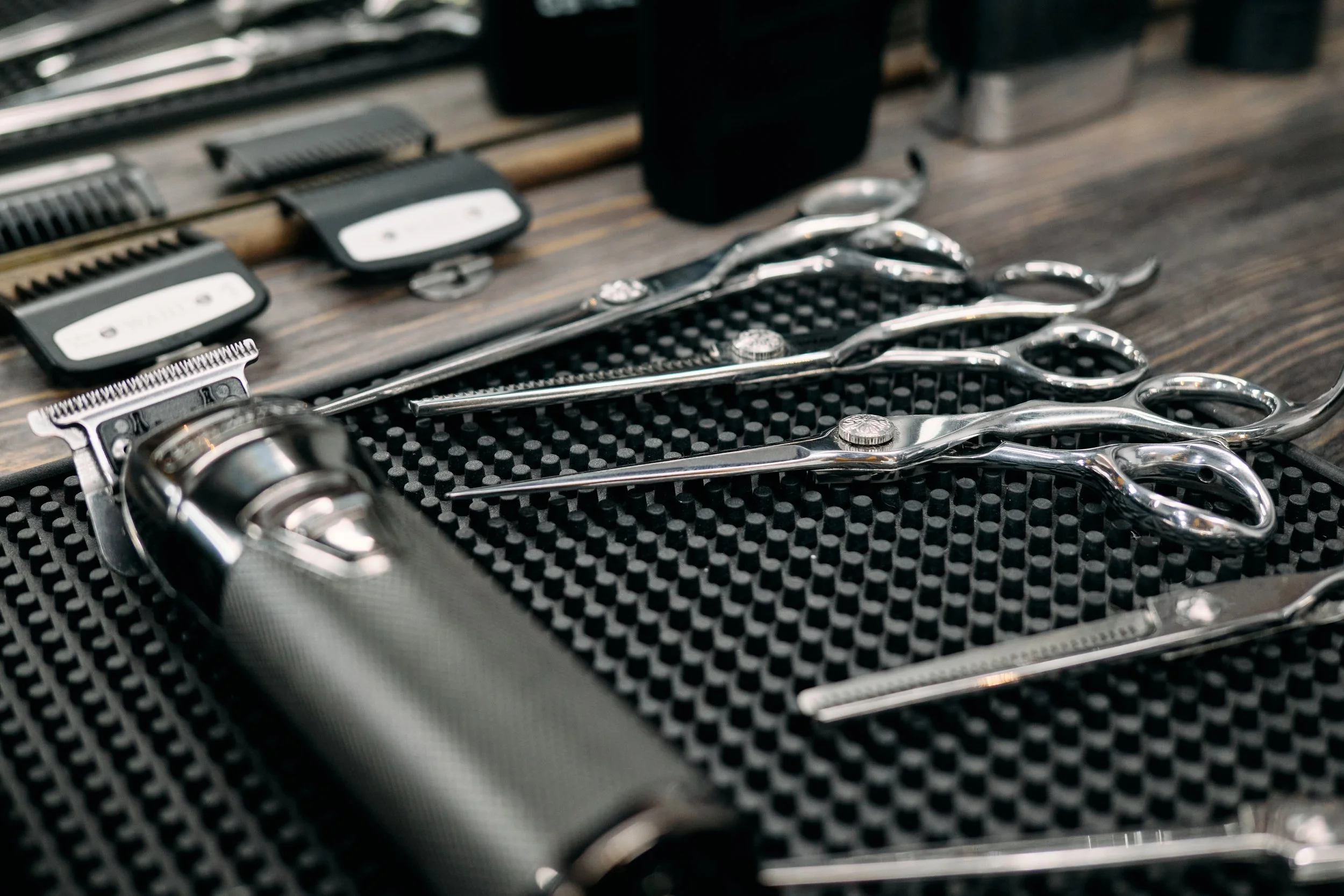 Friseurschere, Handhaarschere, Haarschneideschere und Haarschneidegerät auf einer schwarzen Gummimatte.