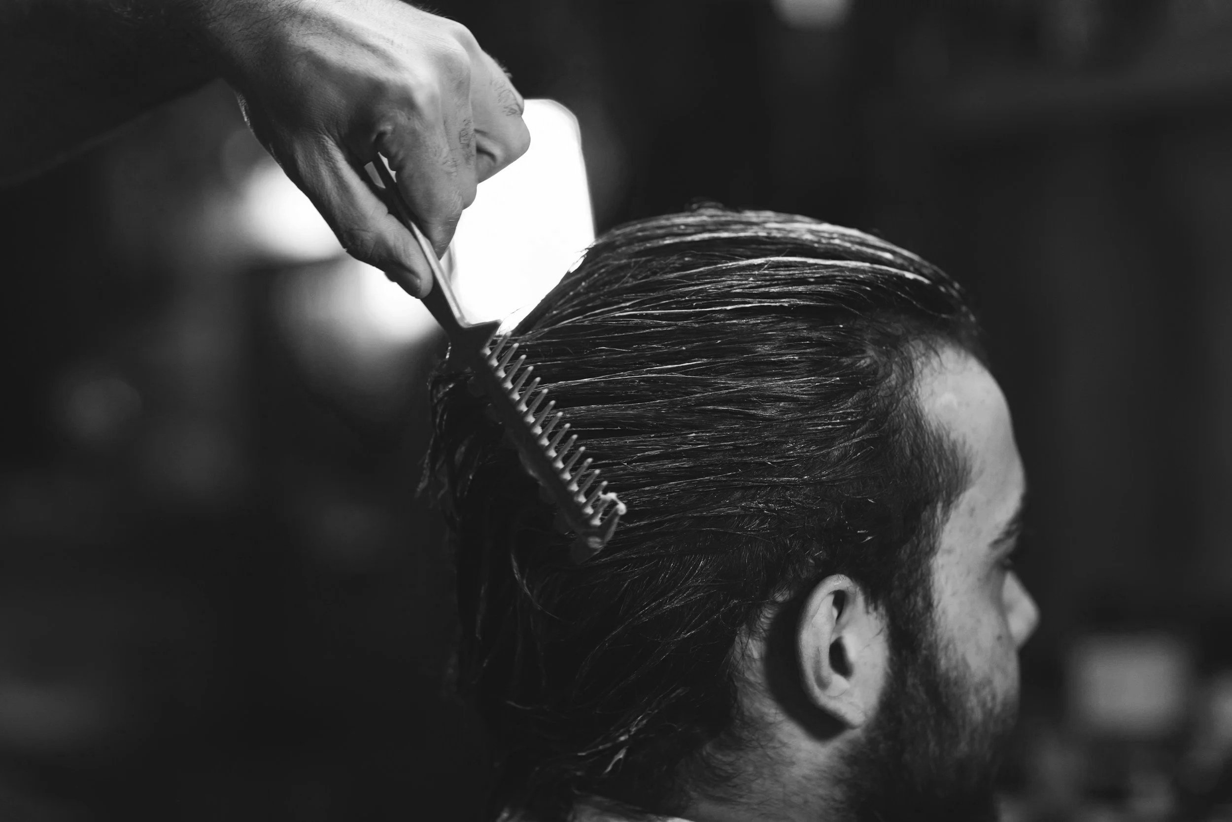 Schwarze und weiße Nahaufnahme einer Person beim Friseur, die Haare geschnitten werden
