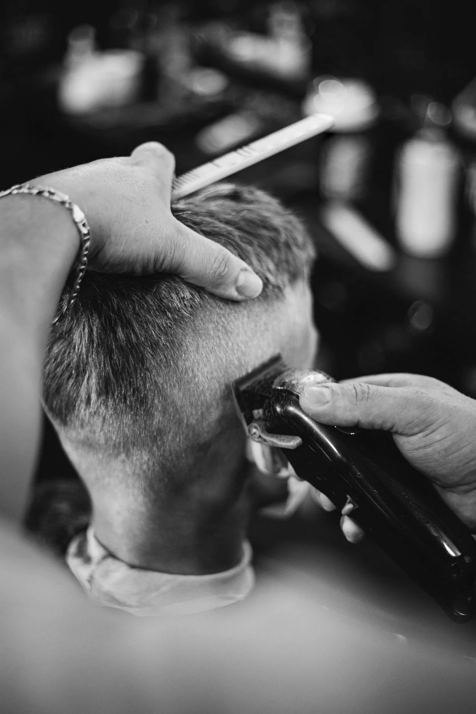 Friseur schneidet einem Kunden die Haare mit Haarschneidemaschine.