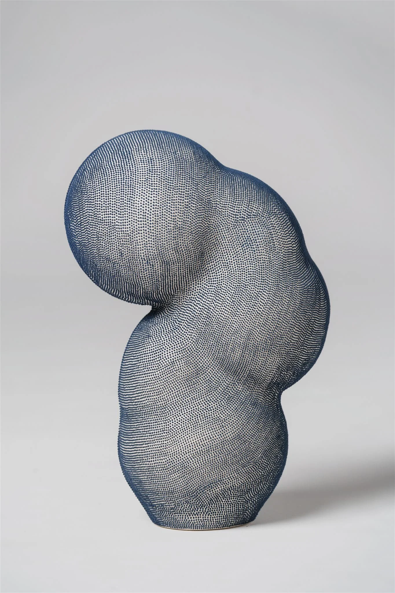 Mamanas IV. Contemporary biomorphic ceramic sculpture with rounded, organic forms. It is covered in dense, hand painted indigo blue dots on an off-white surface
