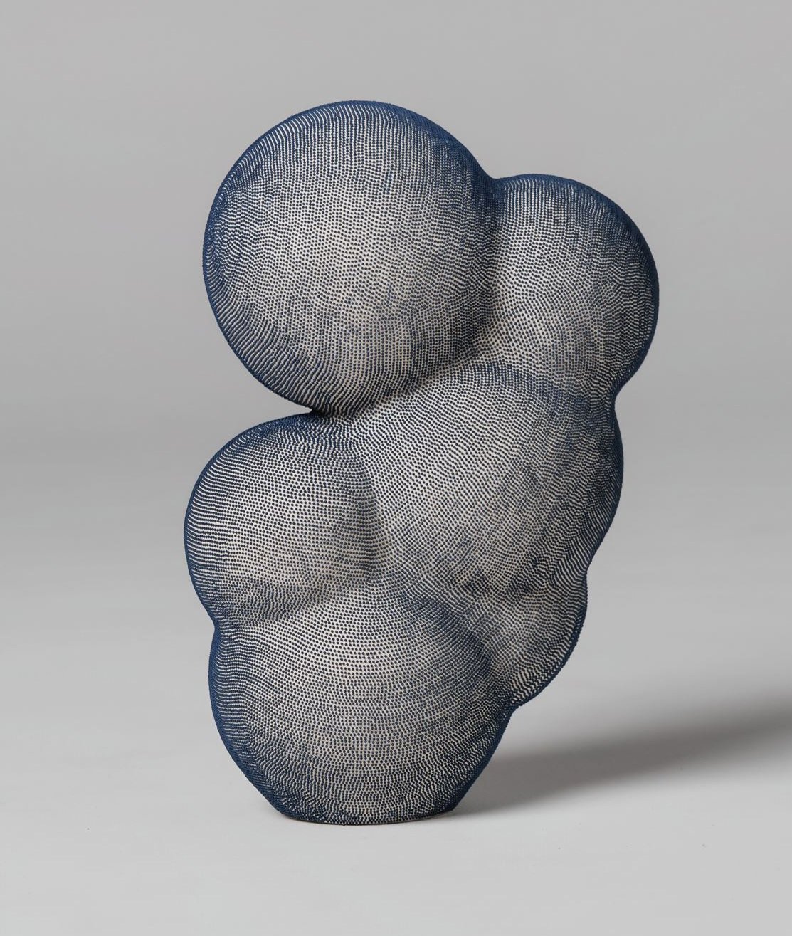 Mamanas VI. A contemporary abstract sculpture with bulbous contours. The piece is composed of dark blue dots that follow the contours of the object. The interplay of these patterns creates a sense of depth.