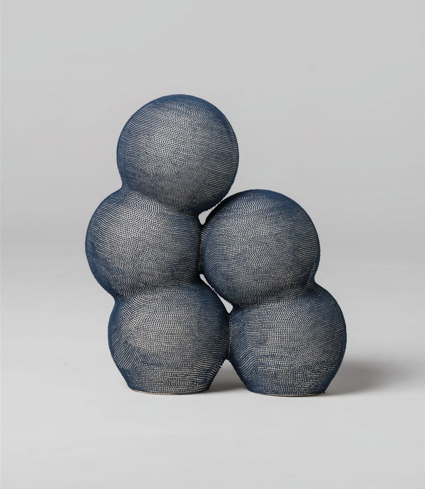 Mamanas I. Ceramic sculpture formed by two interconnected vertical bodies of rounded, anthropomorphic volumes. The surface is densely articulated with hand-applied blue engobe dots, creating a tactile skin that rhythm, memory, and bodily presence.