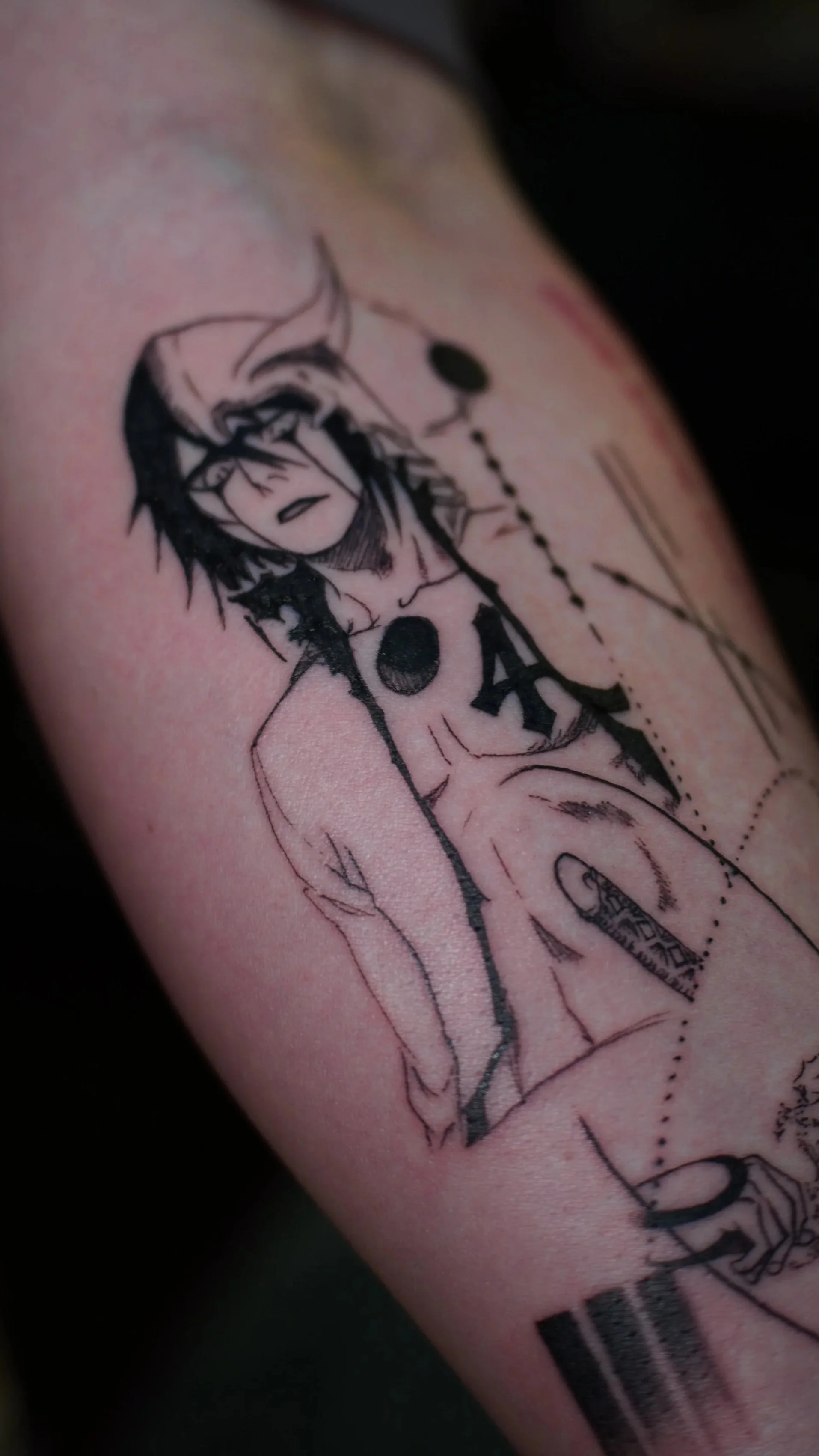 Close-up of a tattoo on skin, depicting a stylized face with dark hair, along with text reading 'PO' and other symbols.