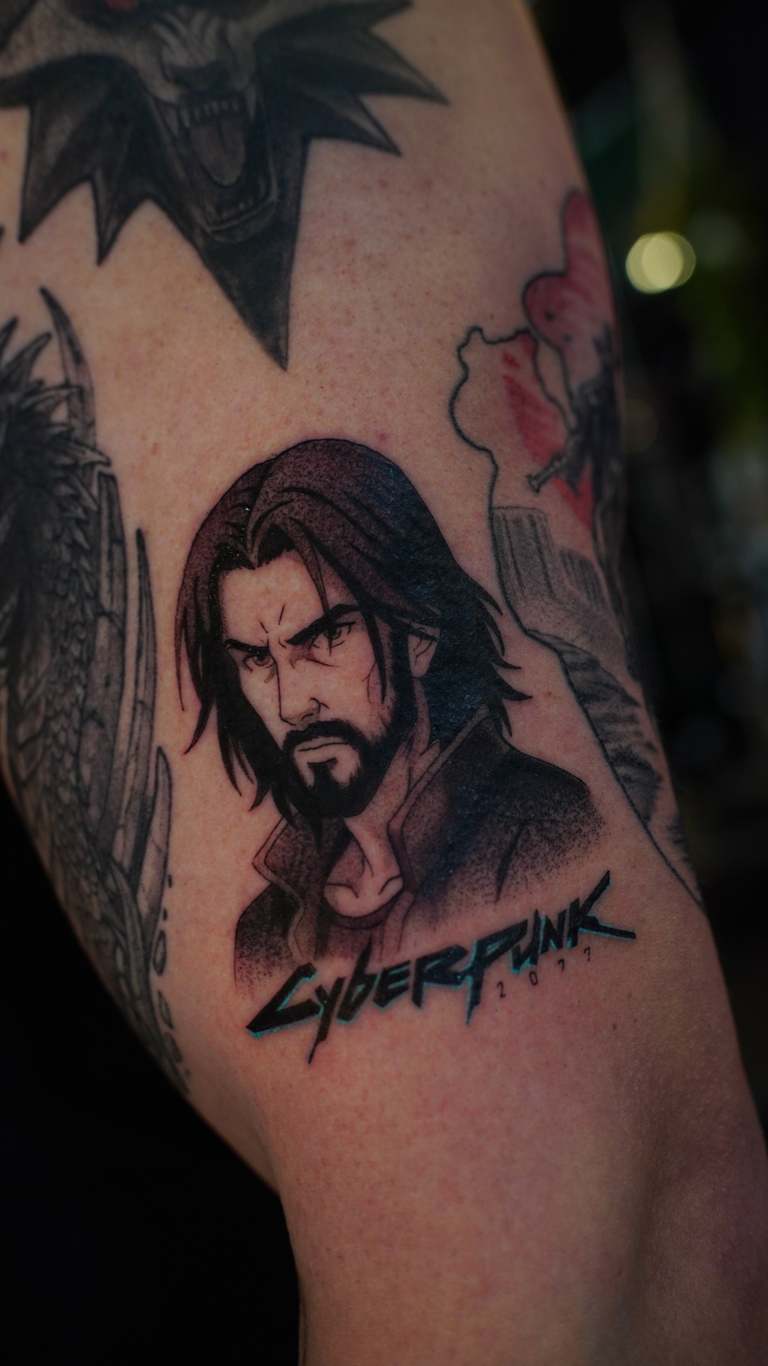 Tattoo of a male character from the video game Overwatch with the text 'Cyberpunk 2077'.