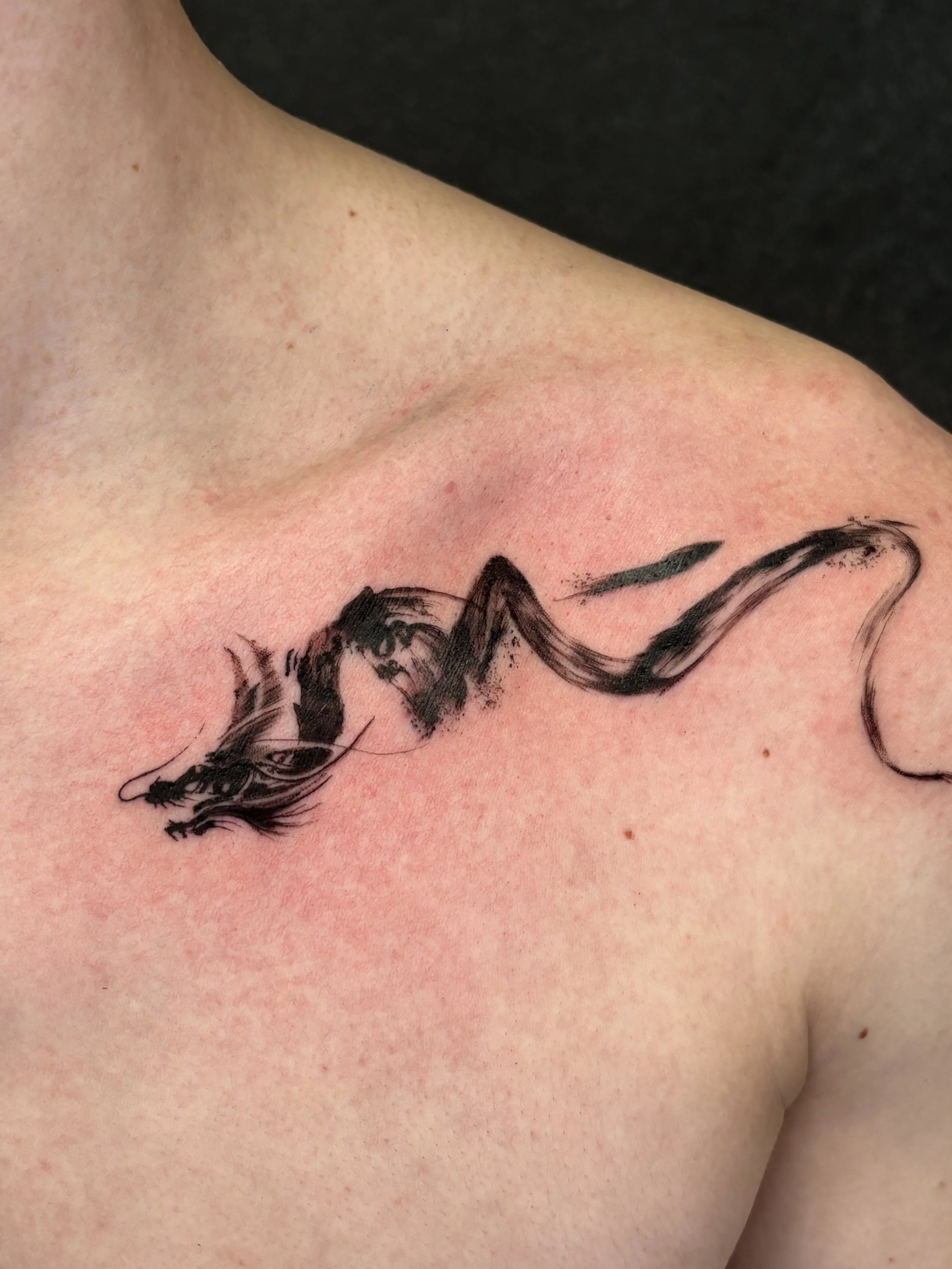 Close-up of a person's chest with a black ink tattoo of a horse and the word 'love'.