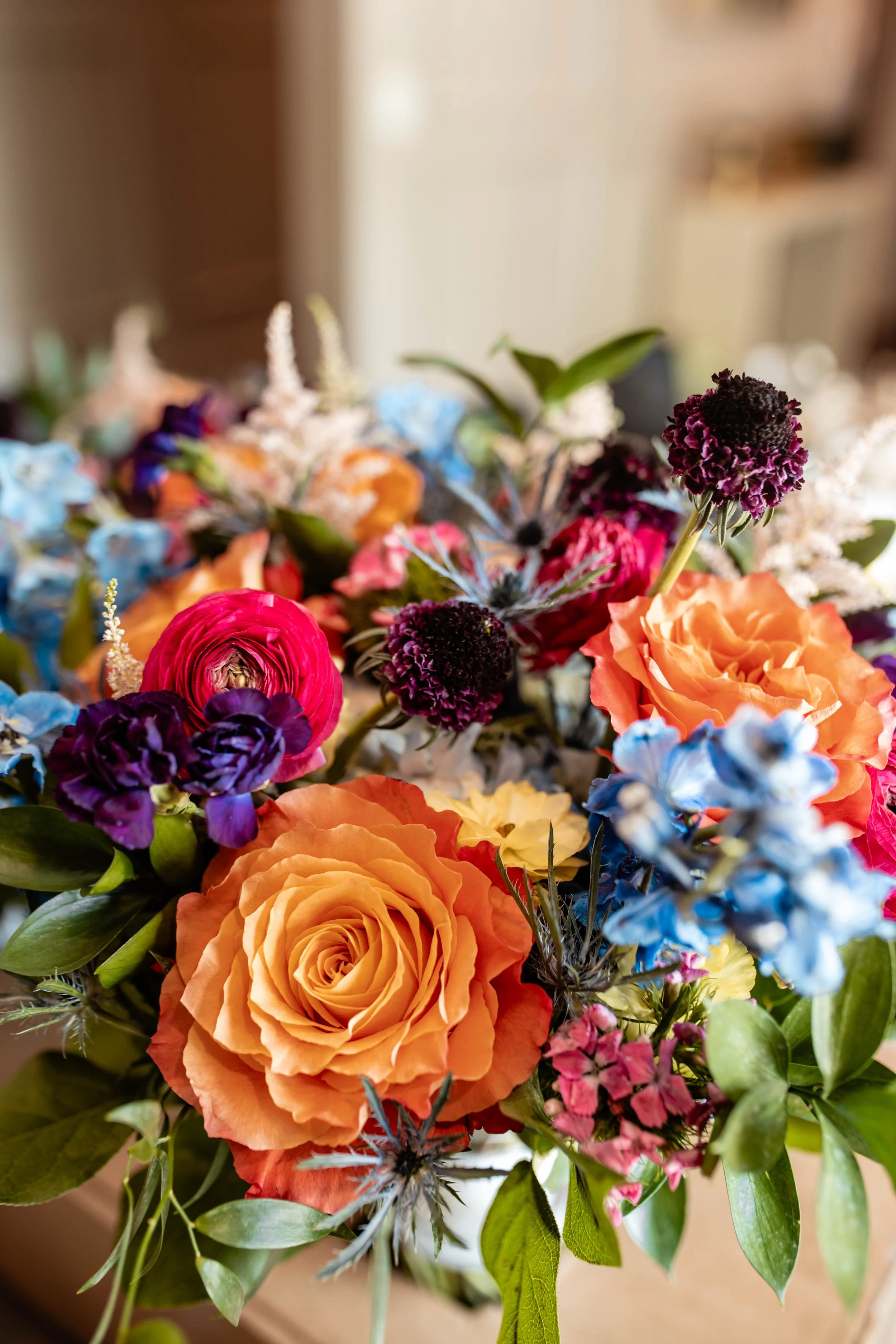 A vibrant bouquet of flowers including orange roses, purple flowers, and various greenery.