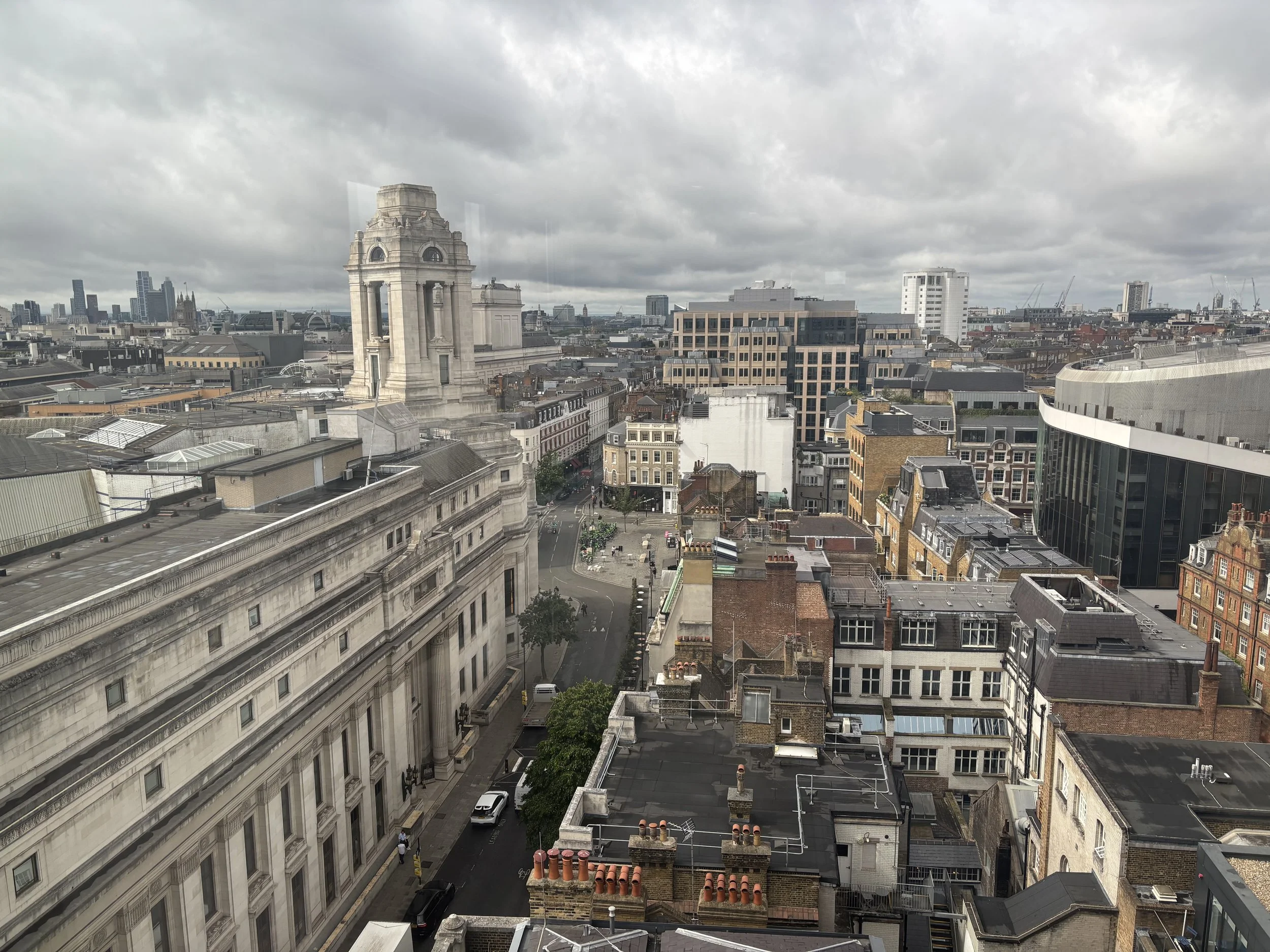 A cityscape view of London with historic and modern buildings under a cloudy sky.