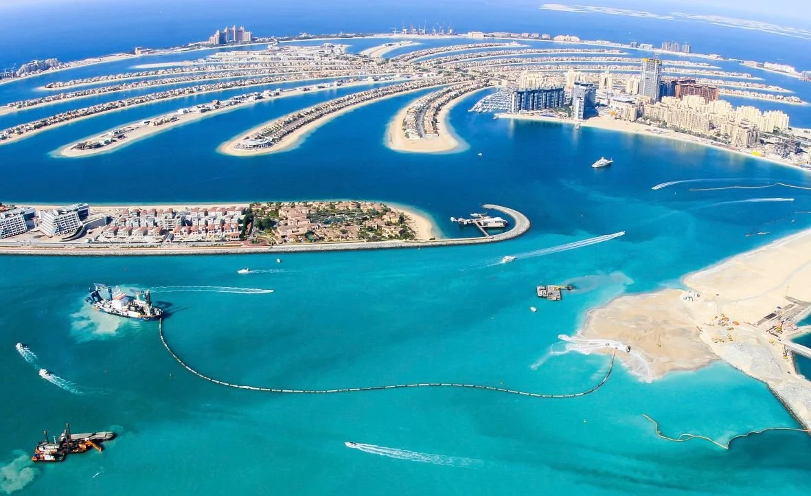 Aerial view of Dubai Atlantis hotel, artificial islands, and waterway with boats in Dubai, United Arab Emirates.
