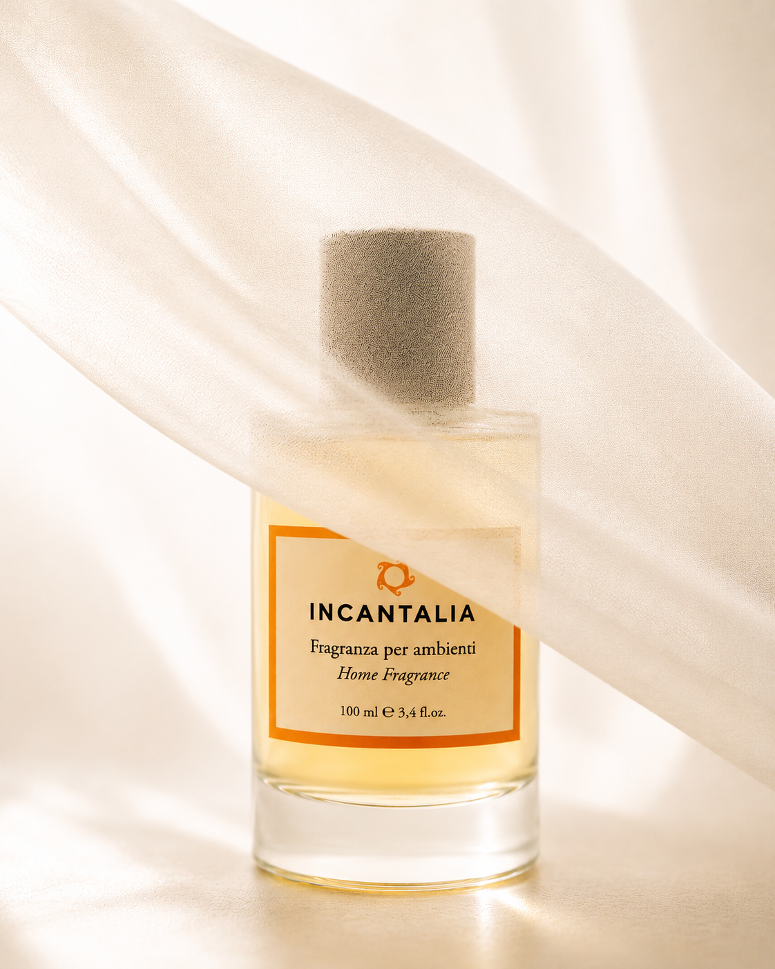 A glass bottle of INCANTALIA home fragrance with a grey cap, partially covered by white fabric.
