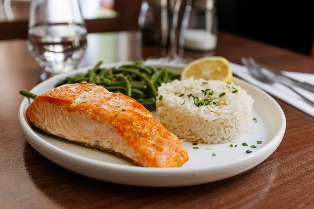 Assiette avec saumon grillé, riz, haricots verts et tranche de citron.