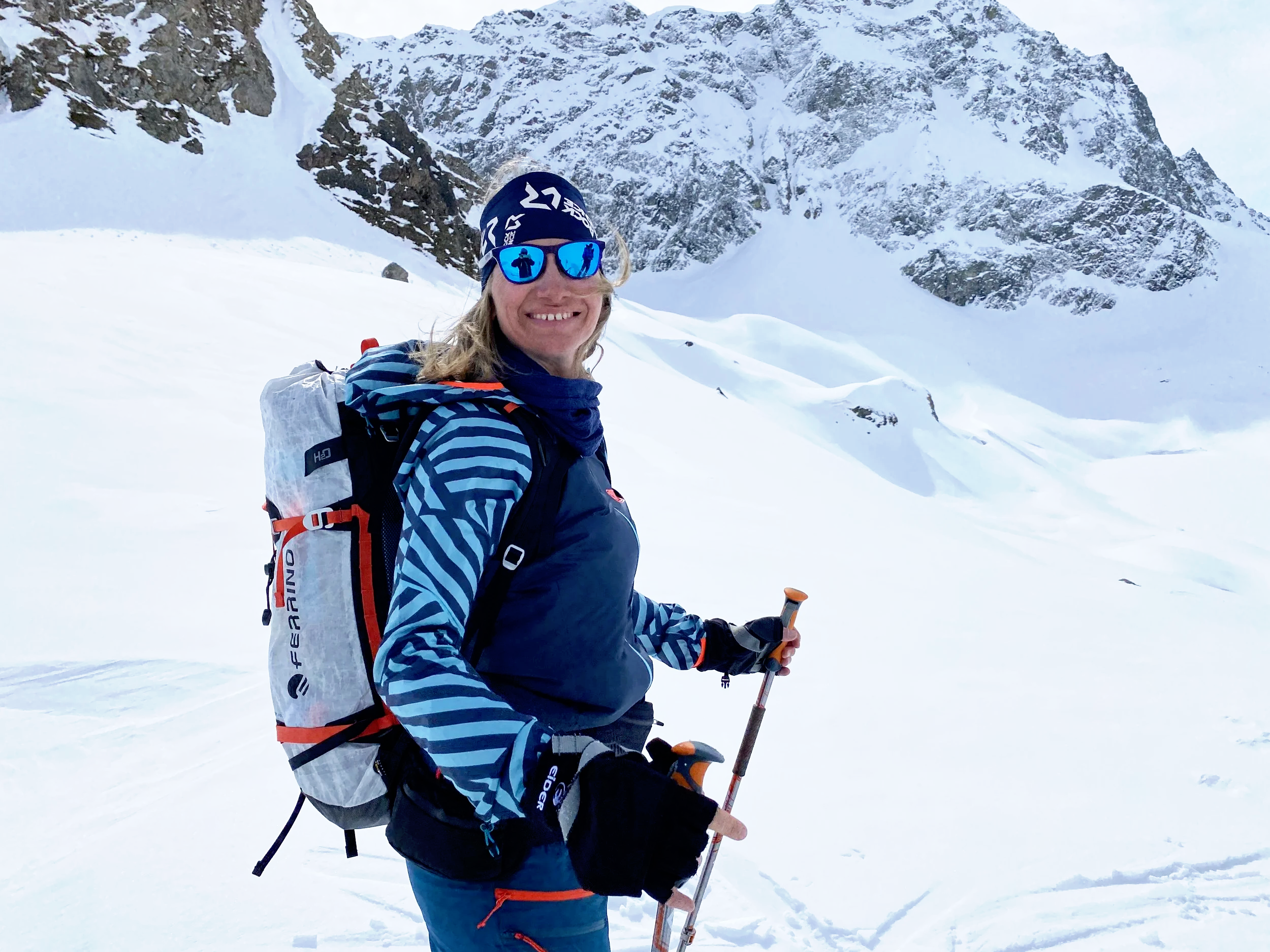 Ski-instructor and mountain enthusiast smiling on a ski tour in front of a mountain background in St. Moritz, Switzerland.