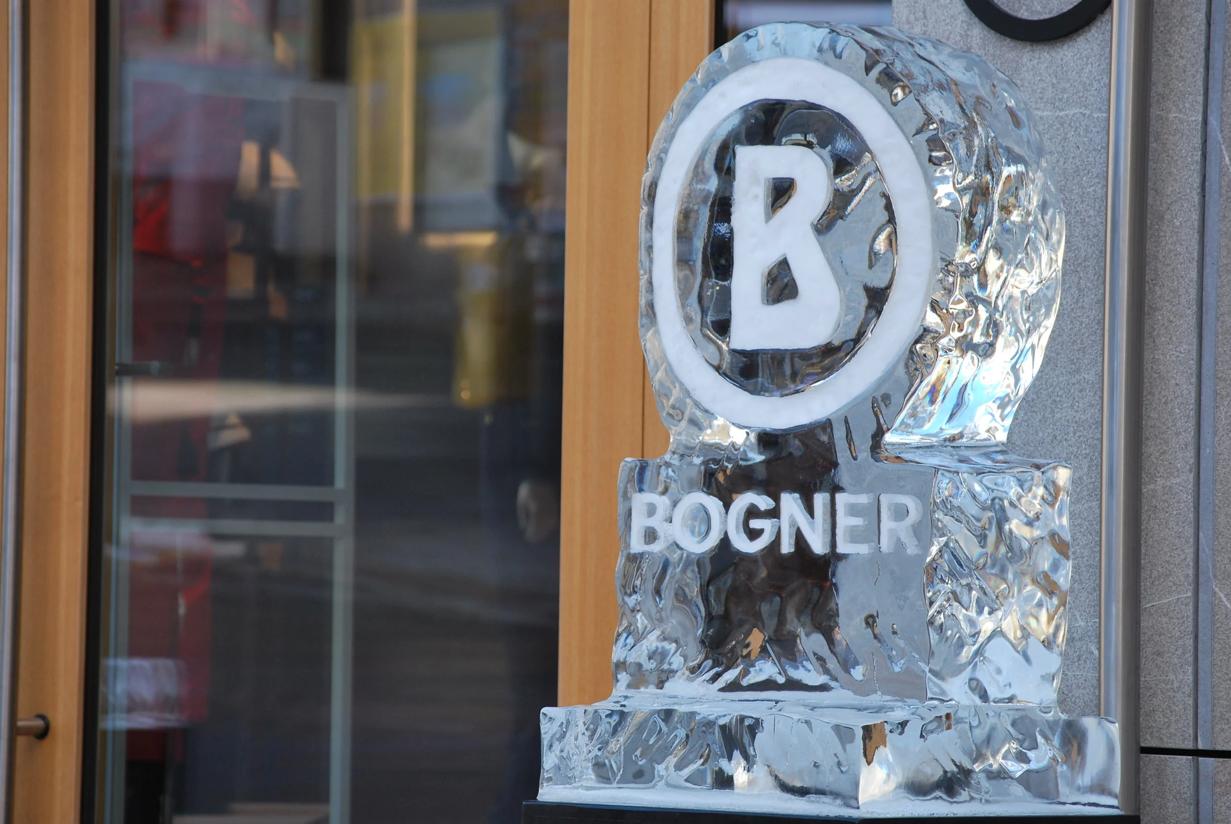 Ice sculpture of the letter R and the words 'Boger' and 'R' with wood and glass background.