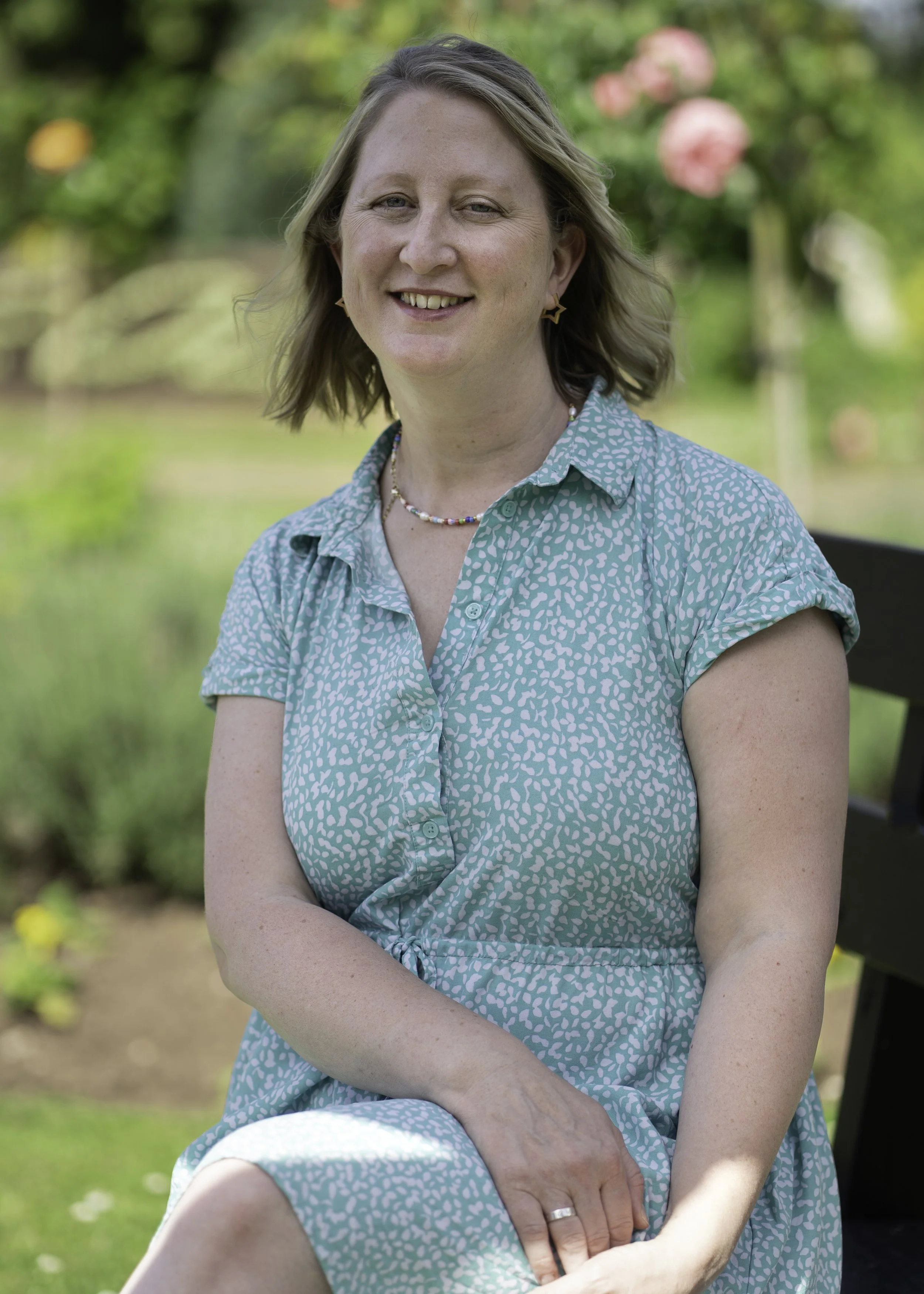 Picture of Sophie Southwell , from Forest Flourish, in Lydney Park on a sunny day surrounded by trees and flowers.