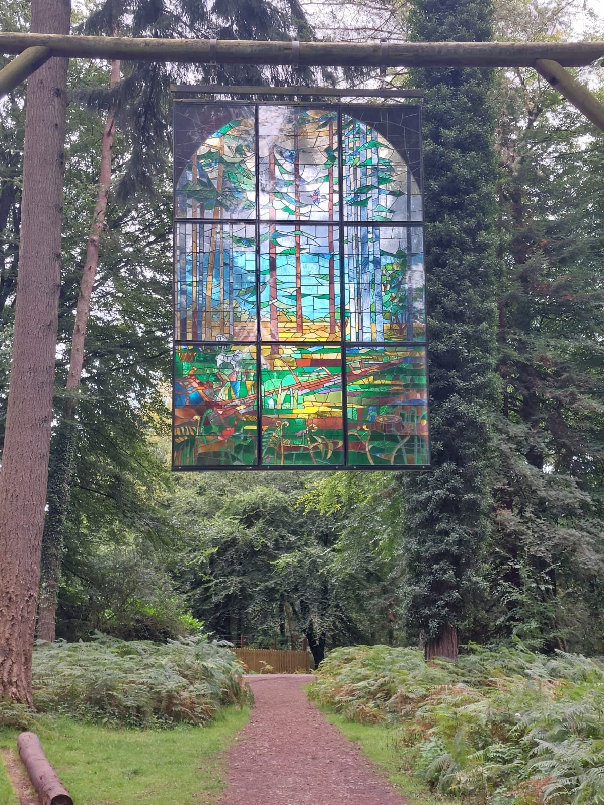 Colourful stained glass artwork hanging in the Forest of Dean, depicting abstract trees and nature scene.