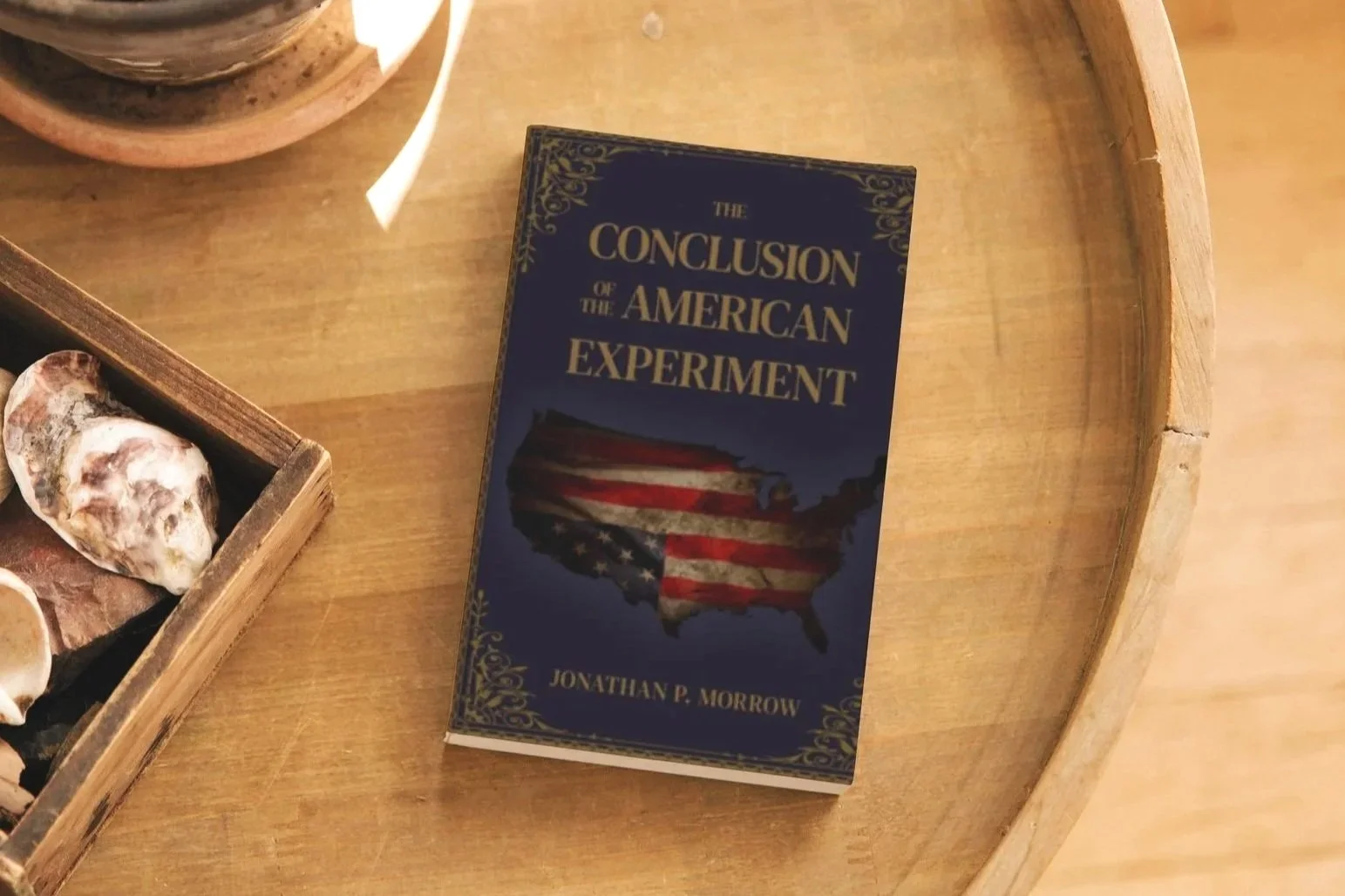 Book titled 'The Conclusion of the American Experiment' by Jonathan P. Morrow resting on a wooden surface.