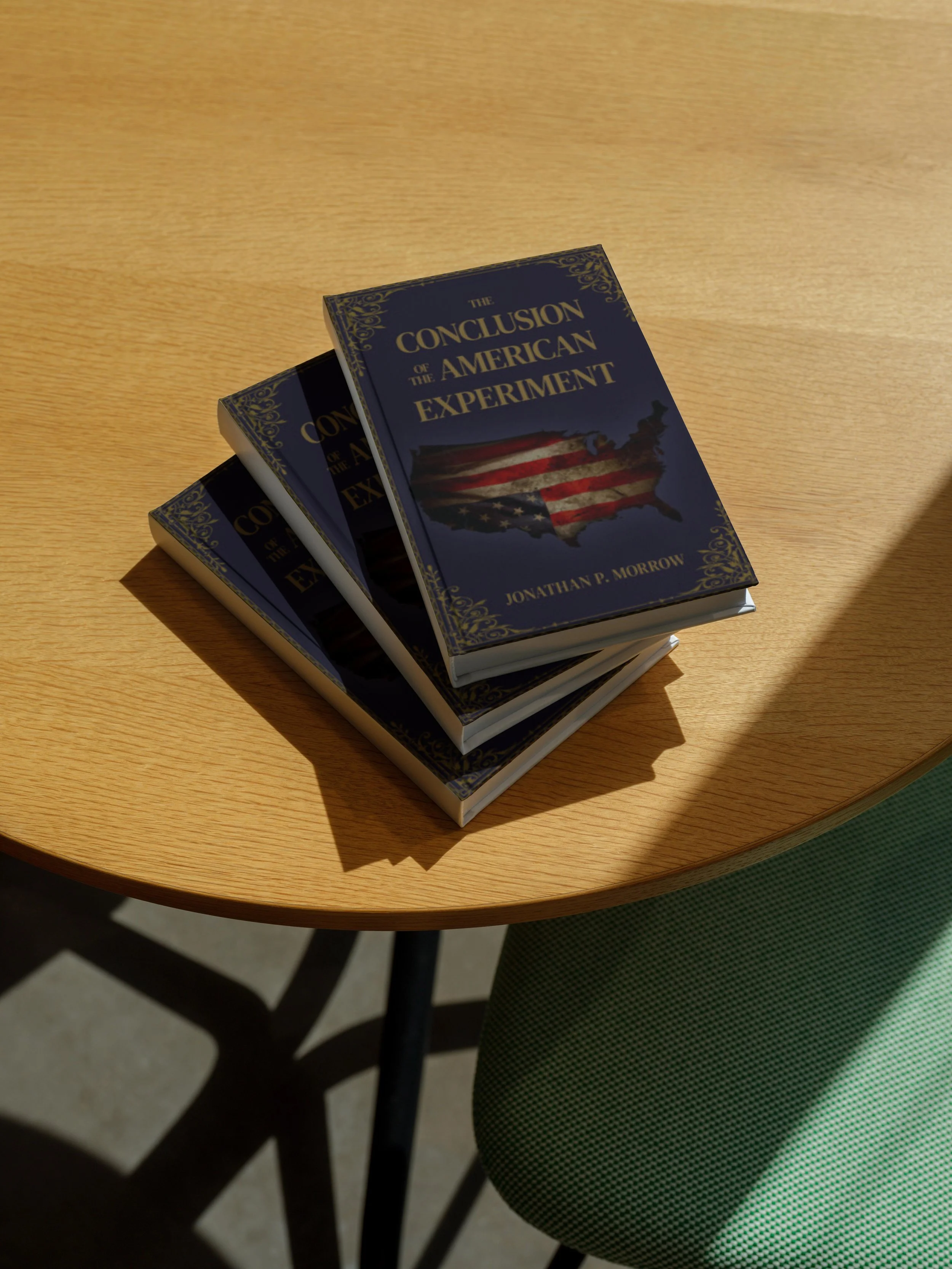 Three copies of a book titled 'The Conclusion of the American Experiment' by Jonathan P. Morrow are stacked on a round wooden table with a shadow cast on the surface.