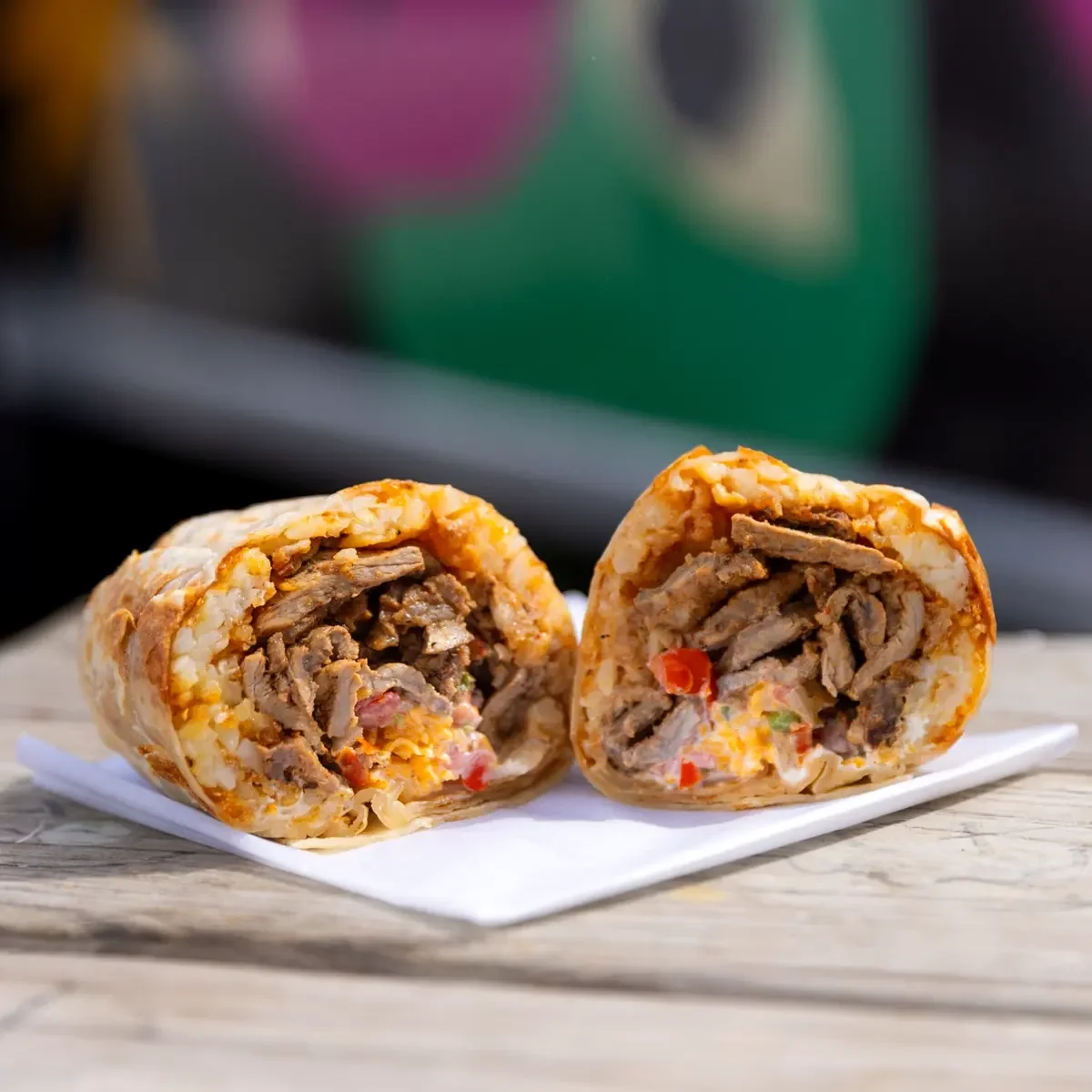 Resting Burrito Face Cali Carne Asada breakfast burrito with carne asada, tots, cheddar, pico de gallo, and crema in Nashville