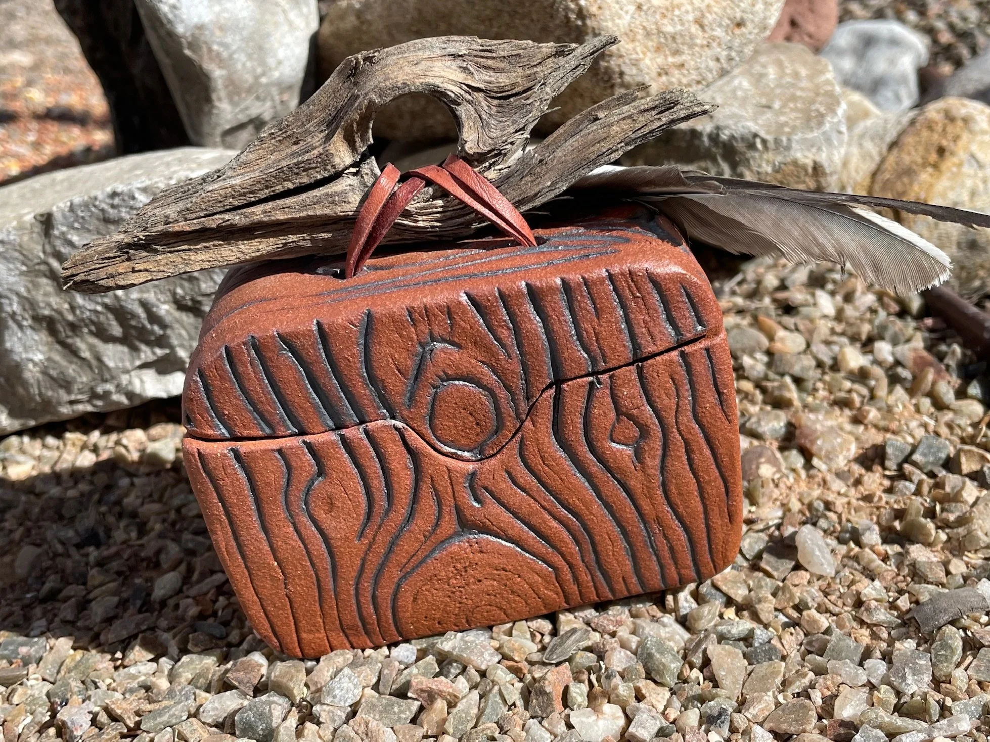 Red clay box, woodgrain, actual roadrunner feathers
