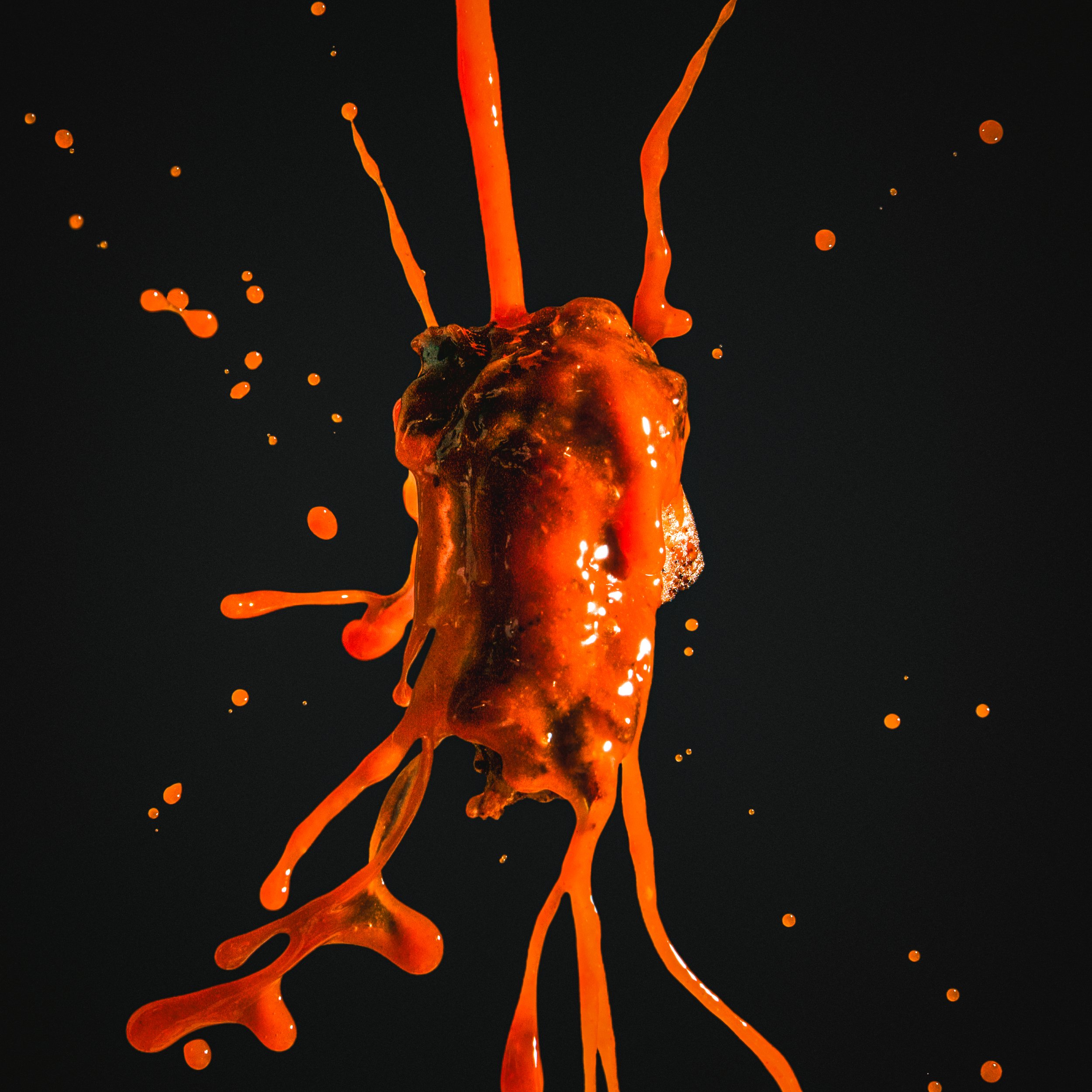 Bright orange liquid splash with droplets on a black background.