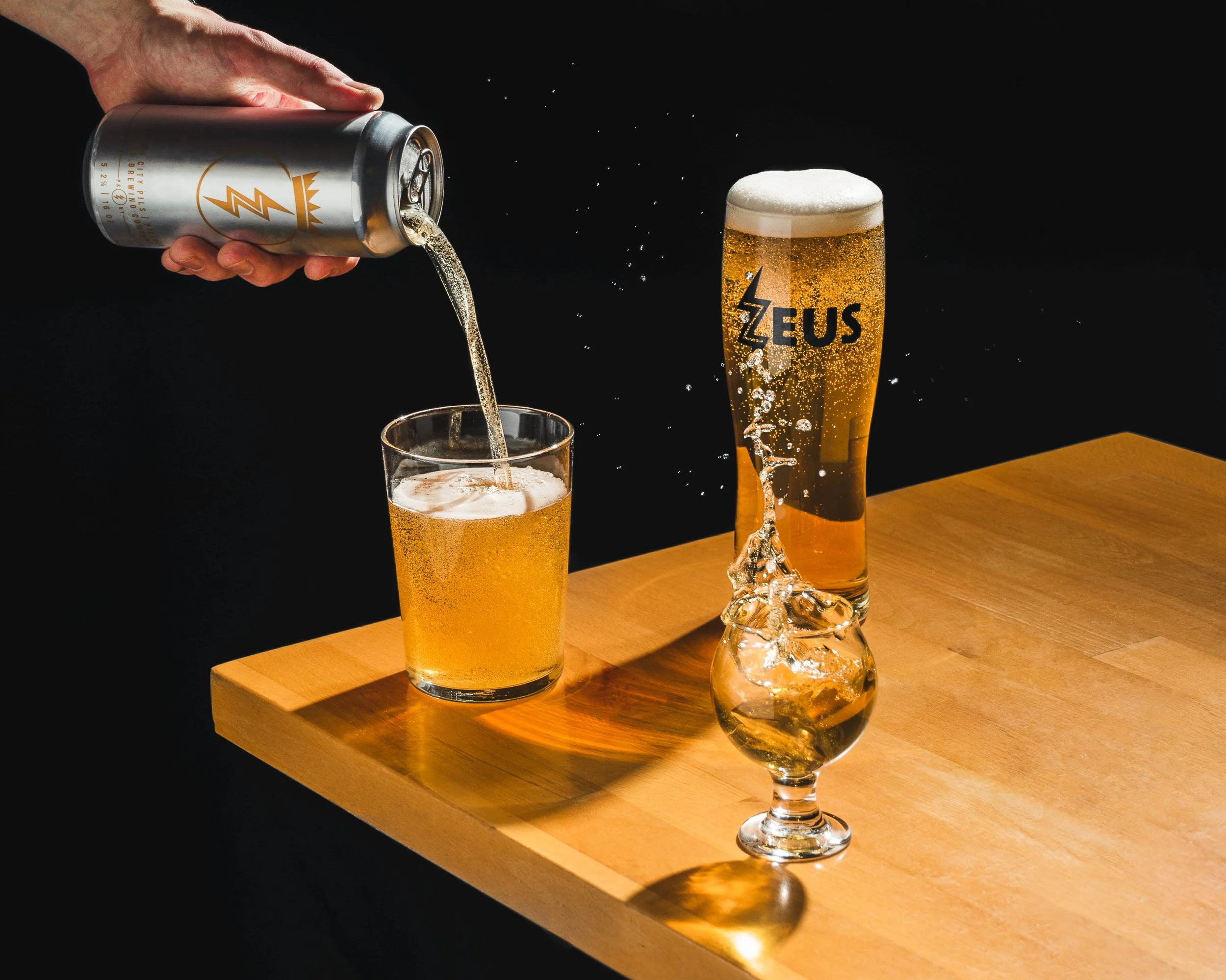Pilsner Beer can and glasses, pouring into glass and splashing - dramatic cinematic food photography - Hudson Valley, Poughkeepsie, NY