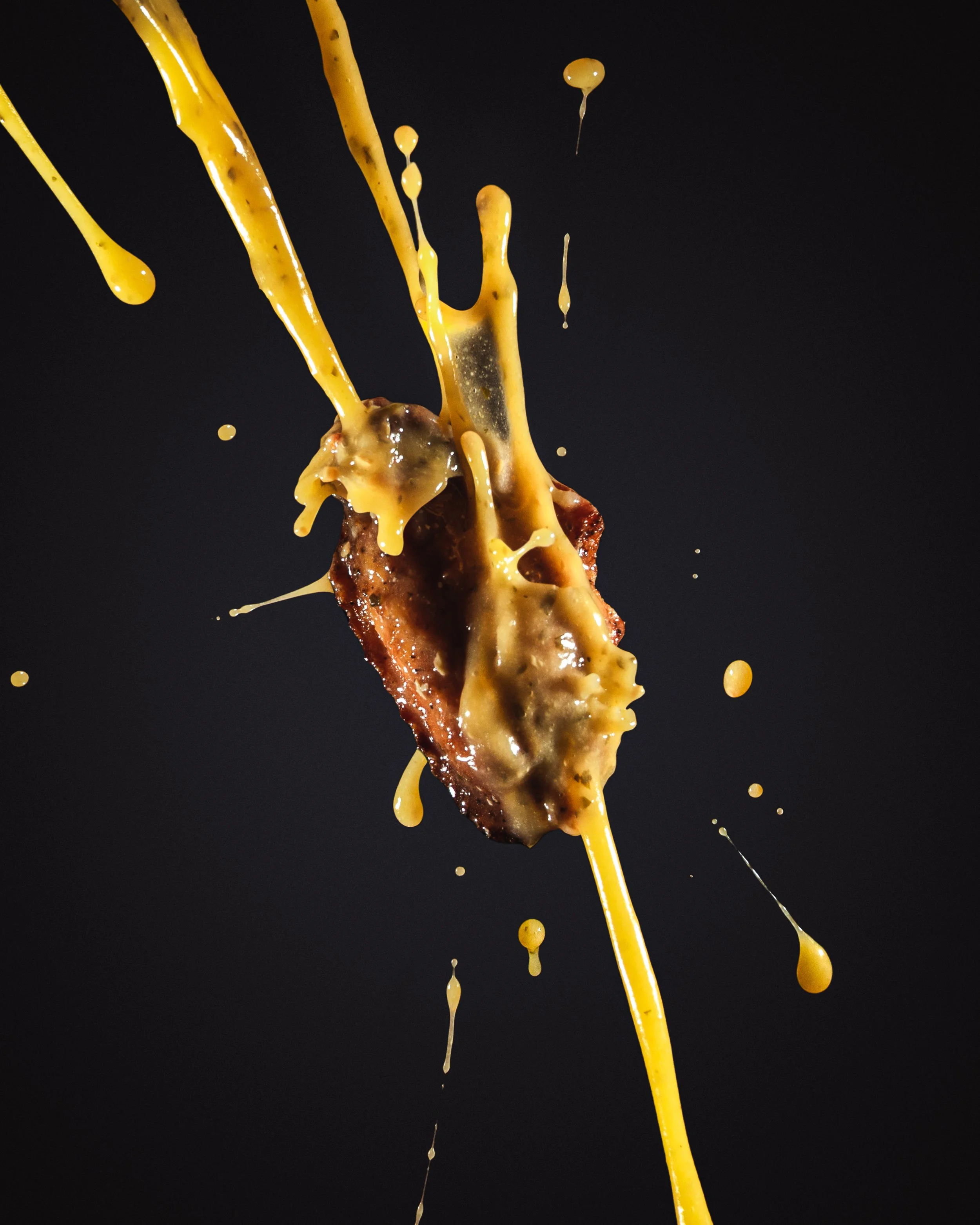 Close-up of bacon strip with mustard splash on a black background.