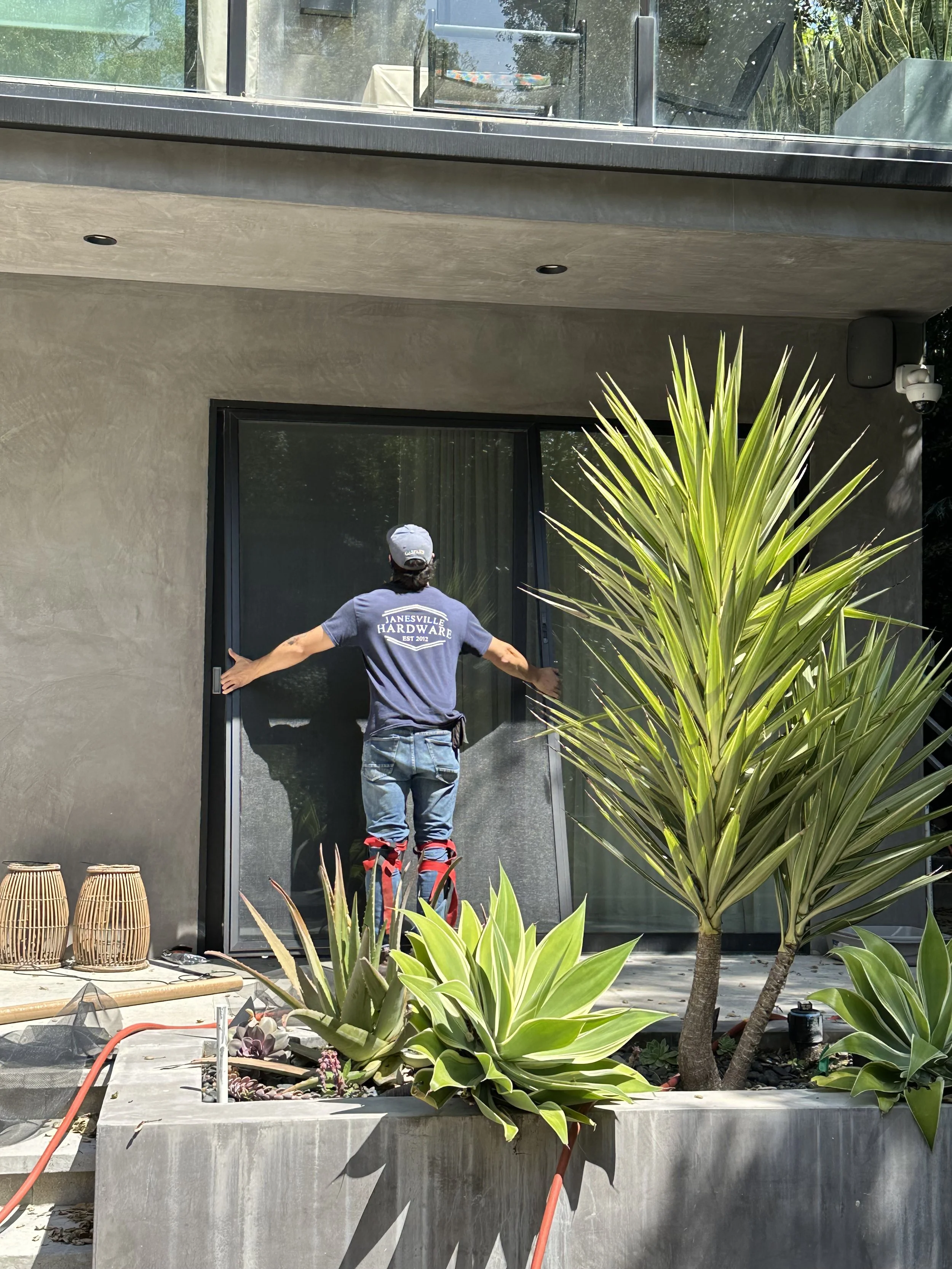 Technician inspecting large sliding glass door during property care service in Los Angeles.