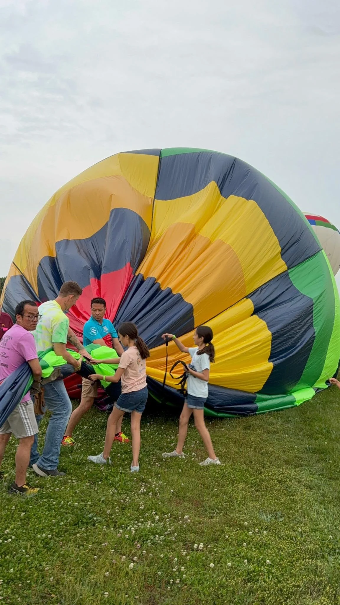 The team helping to deflate hot air balloon on a grassy field.