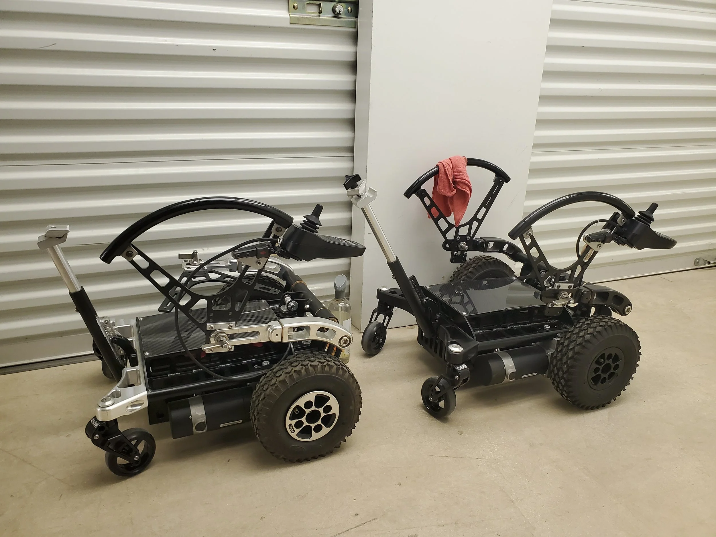 Two power-flex devices parked indoors against a white wall with horizontal ridges. 