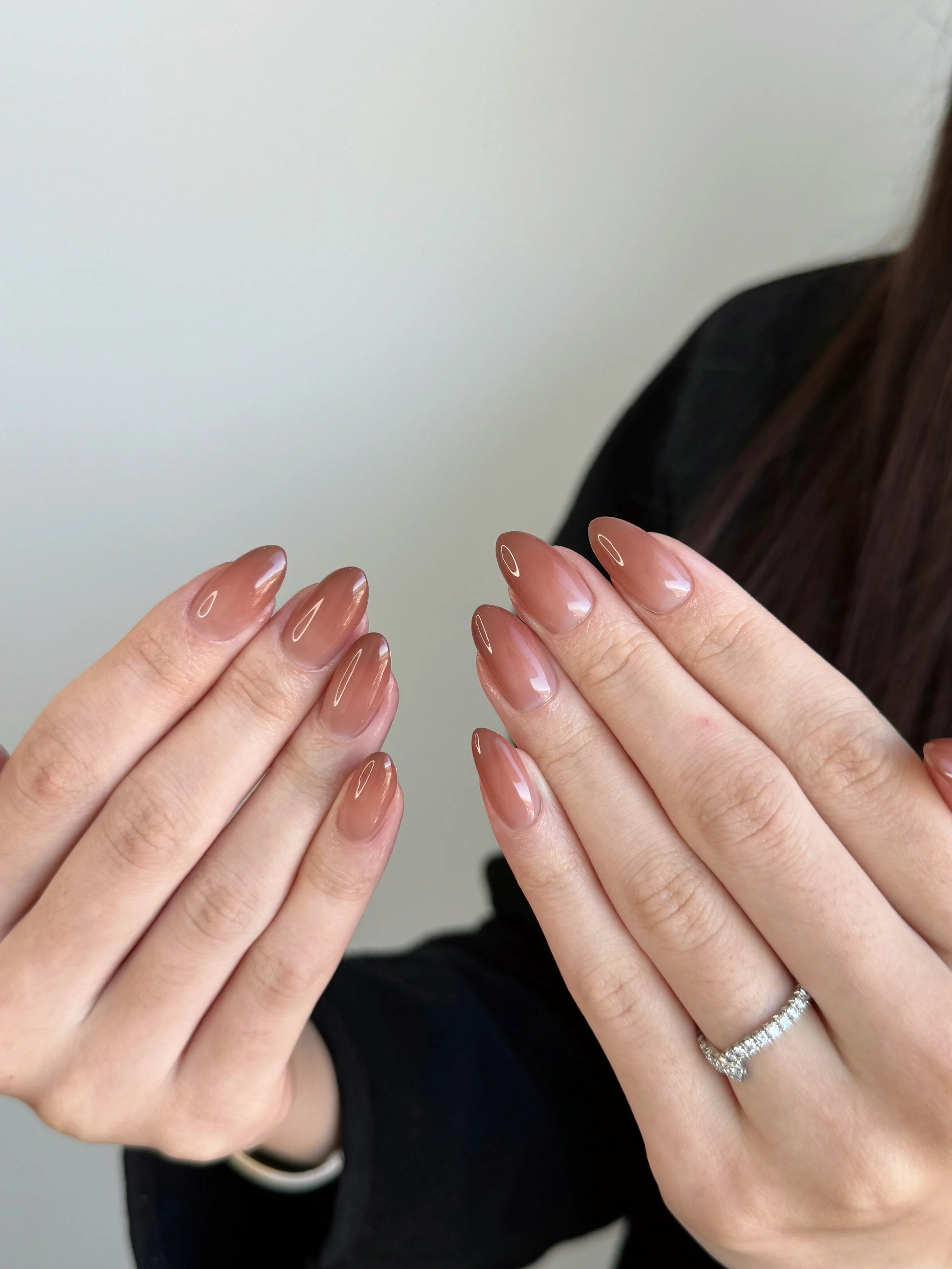A person showing off their freshly manicured nails painted in a nude color.