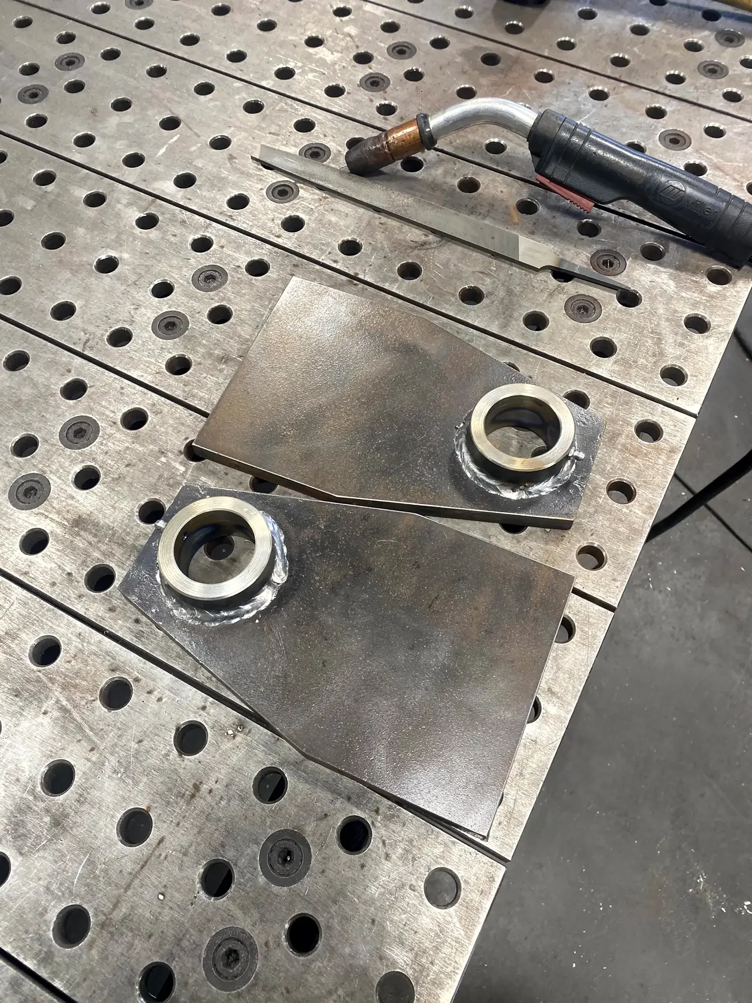 Metal workbench with a welding torch and welded metal components.