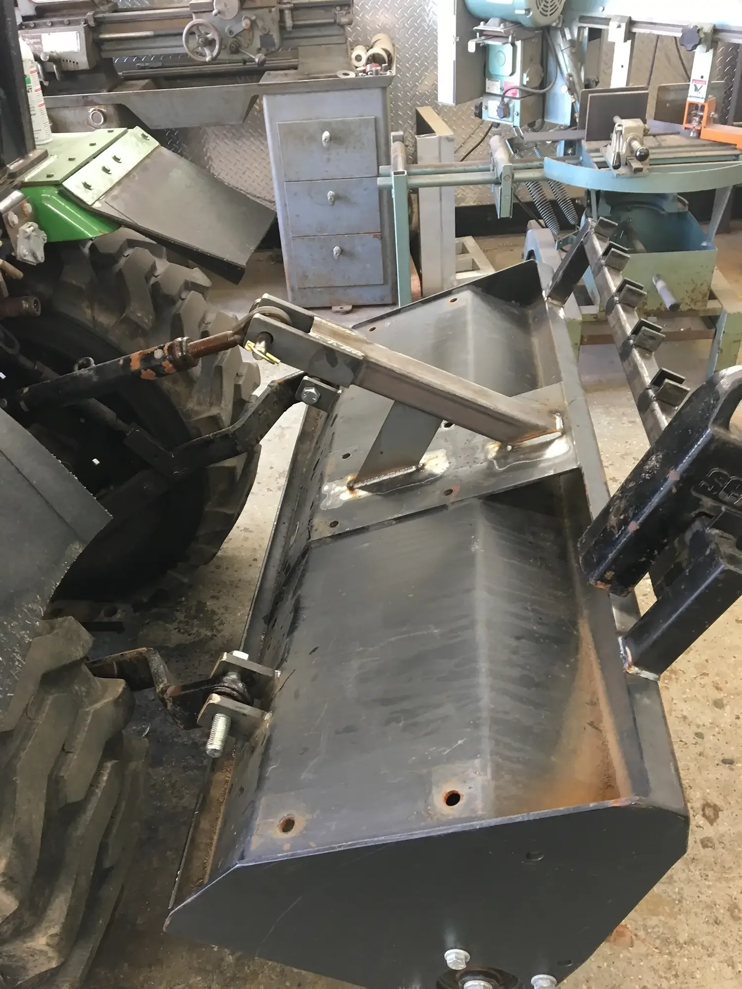 Metal machinery with conveyor belt and mechanical components in a workshop or industrial setting.