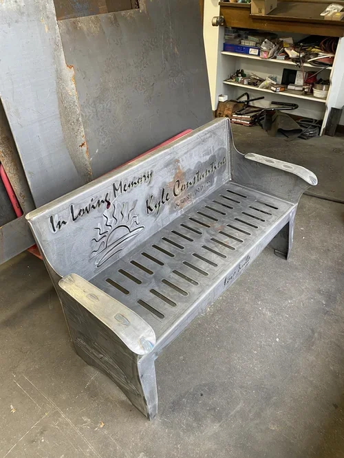 Metal bench with an engraved sunset and the words 'In Loving Memory of Katie Casteel'