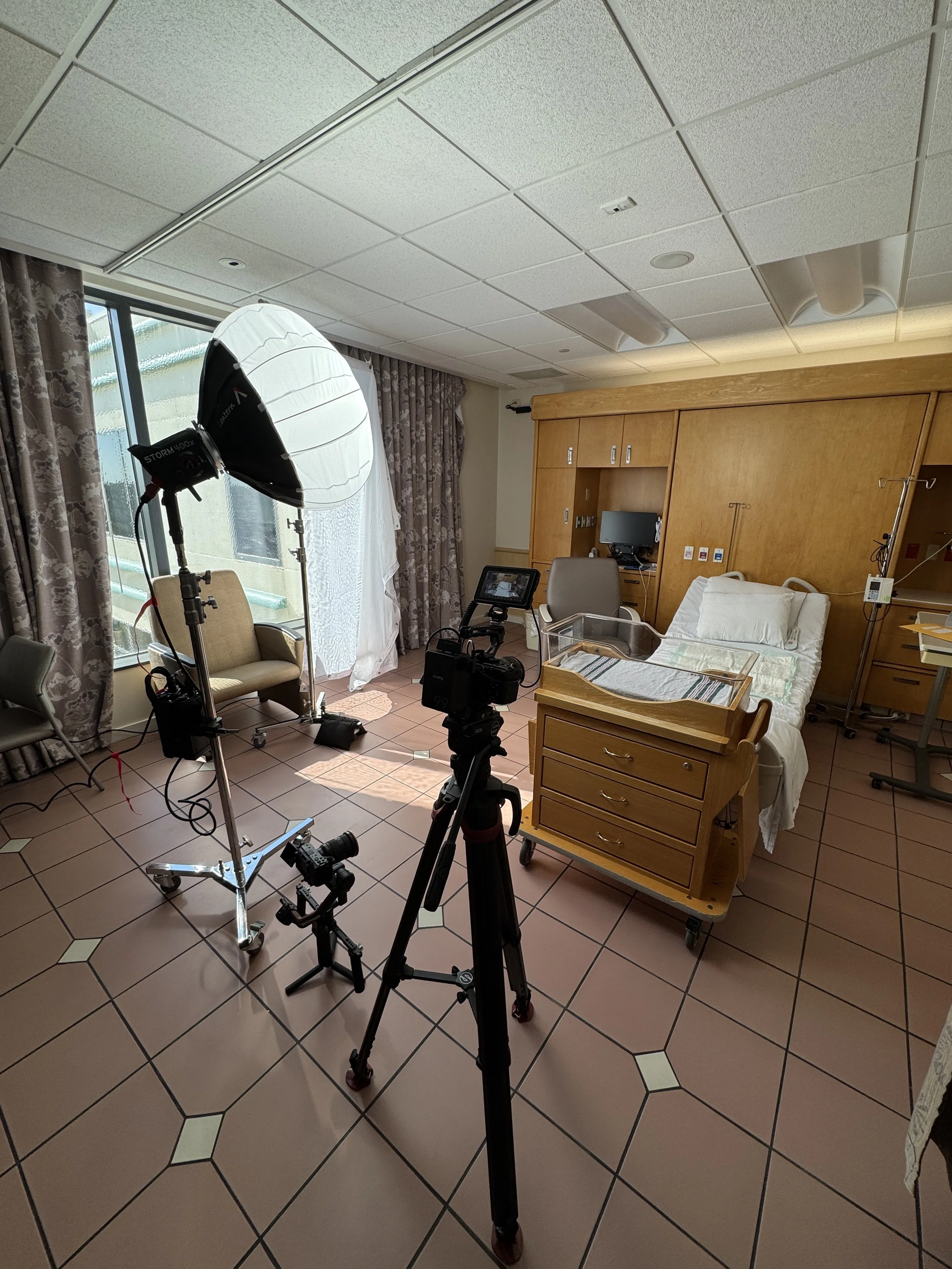 Hospital room with medical equipment, a hospital bed, a monitor, an IV stand, and professional lighting setup.