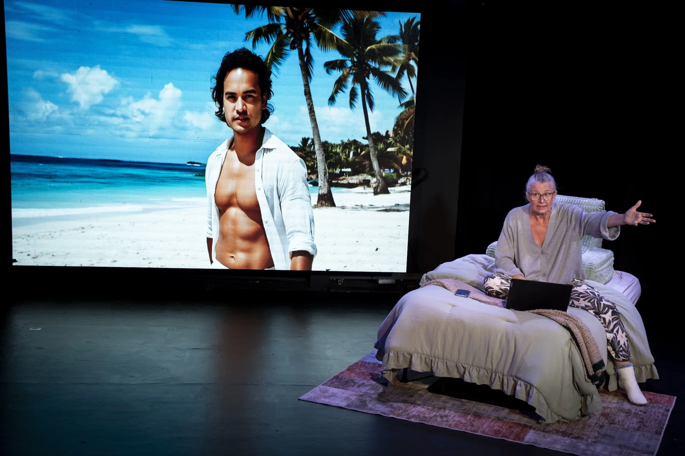 SJ Hodges as Susan with Ai Matteo in the background in a production still from Already Here, a play exploring grief, love, and artificial intelligence.