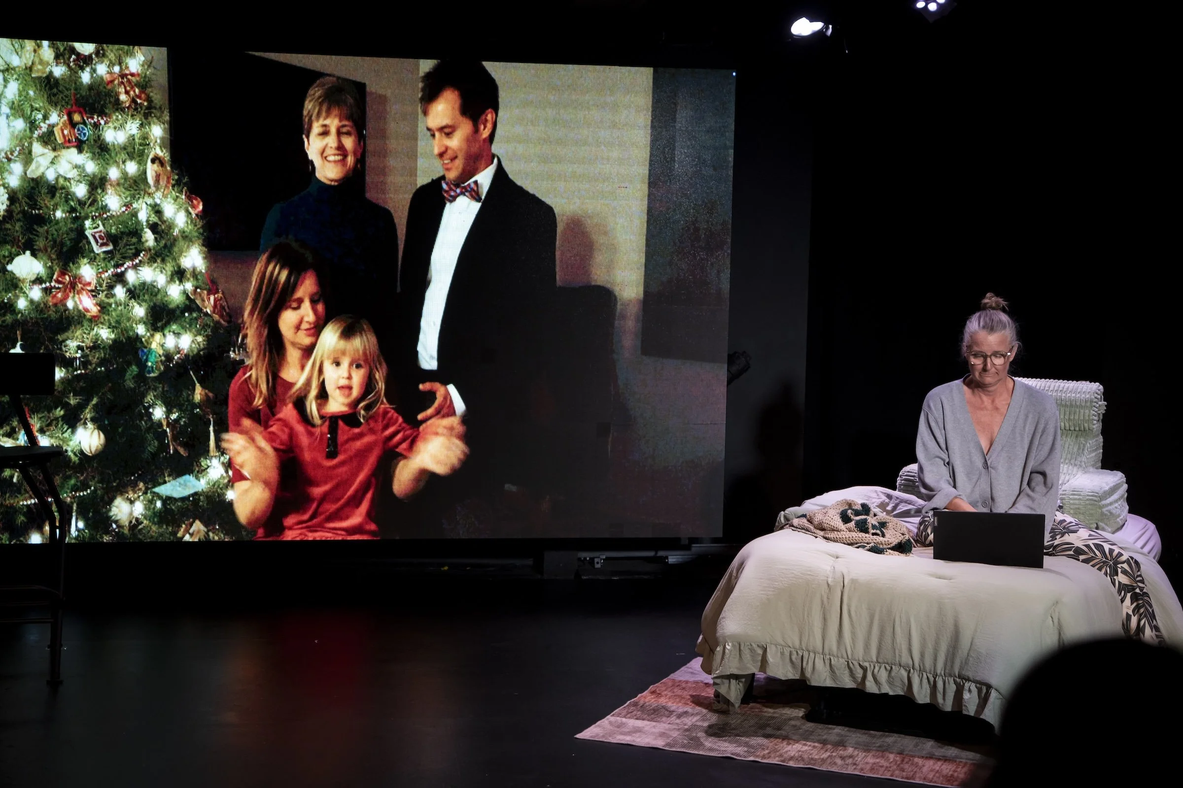 Susan/SJ Hodges typing on a lap on on her bed with a photo of her family in the background
