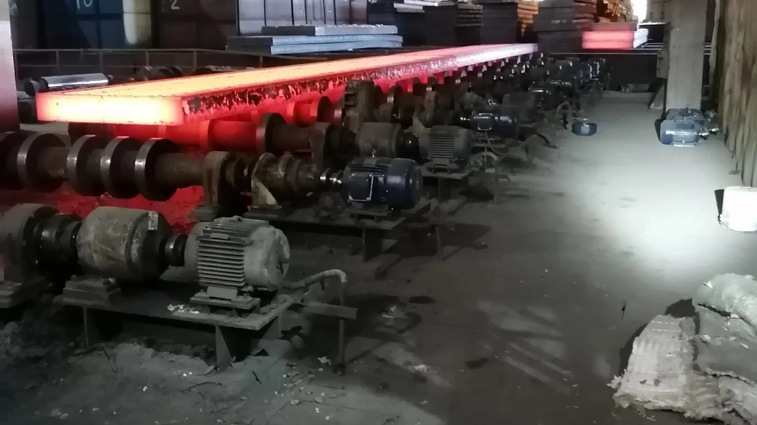 Máquinas y componentes industriales en un taller, algunos con luces rojas y otras de luz blanca, en un ambiente oscuro.