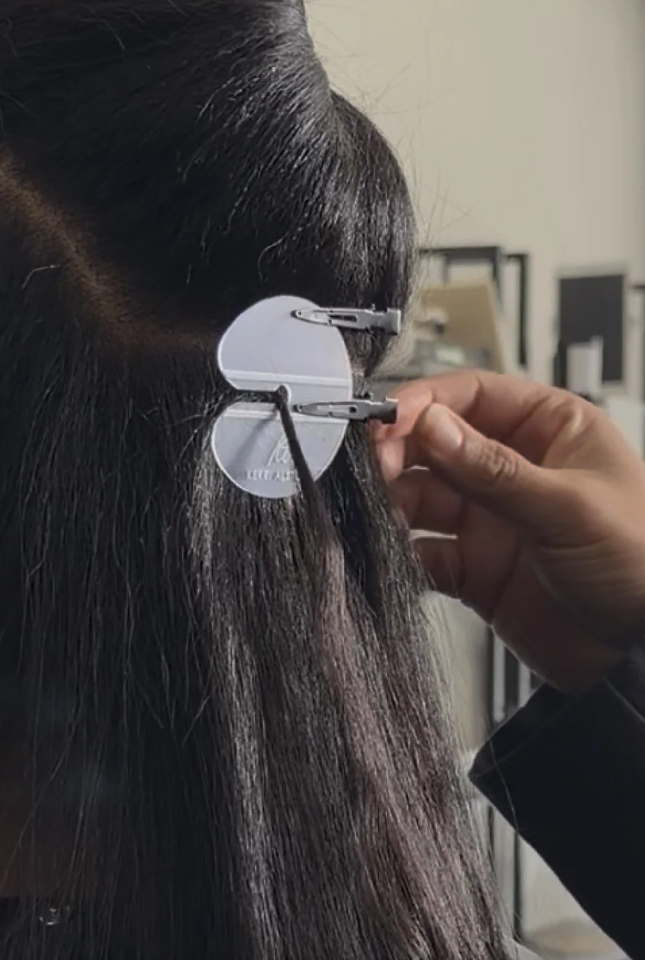 Close-up of a person’s face with a hearing aid being inserted by a hand.
