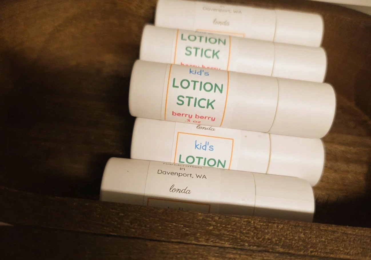 Several tubes of kid's lotion sticks labeled 'berry berry' and 'londa' in a wooden container.