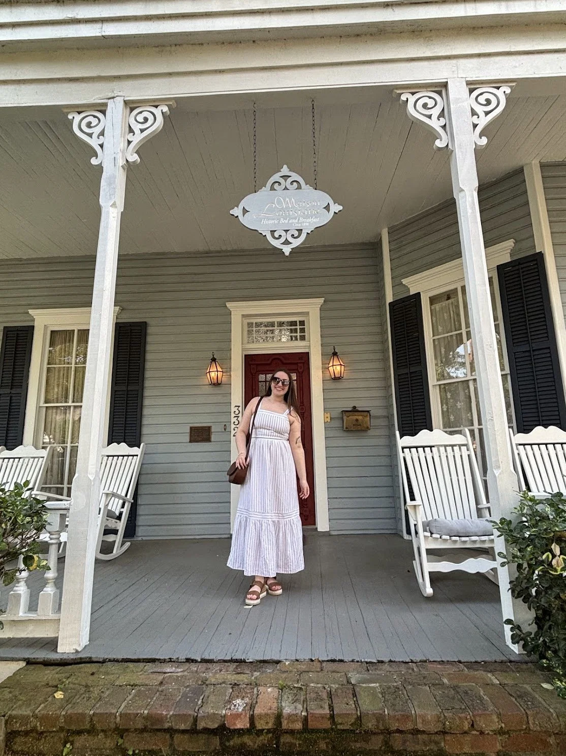  woman stands on the porch of a historic home in Natchitoches, Louisiana  