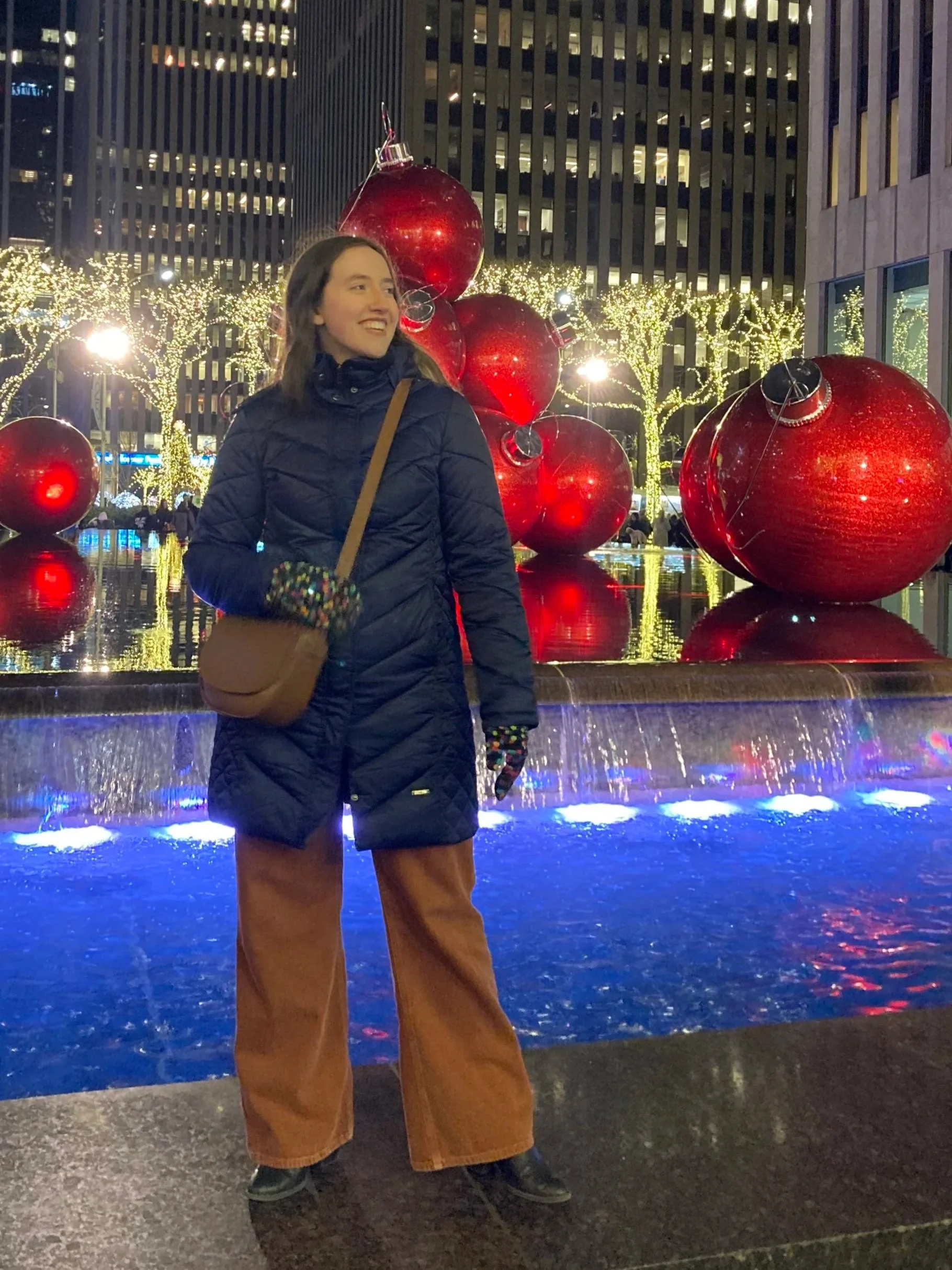 Traveler in front of lights and Christmas decorations in New York City.